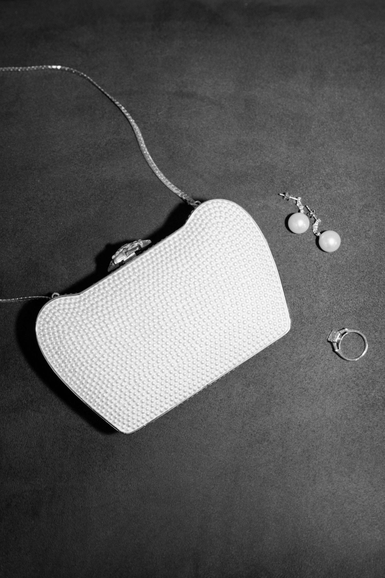 Black and white photo sequence showing a white clutch purse with jewelry accessories on a dark surface.
