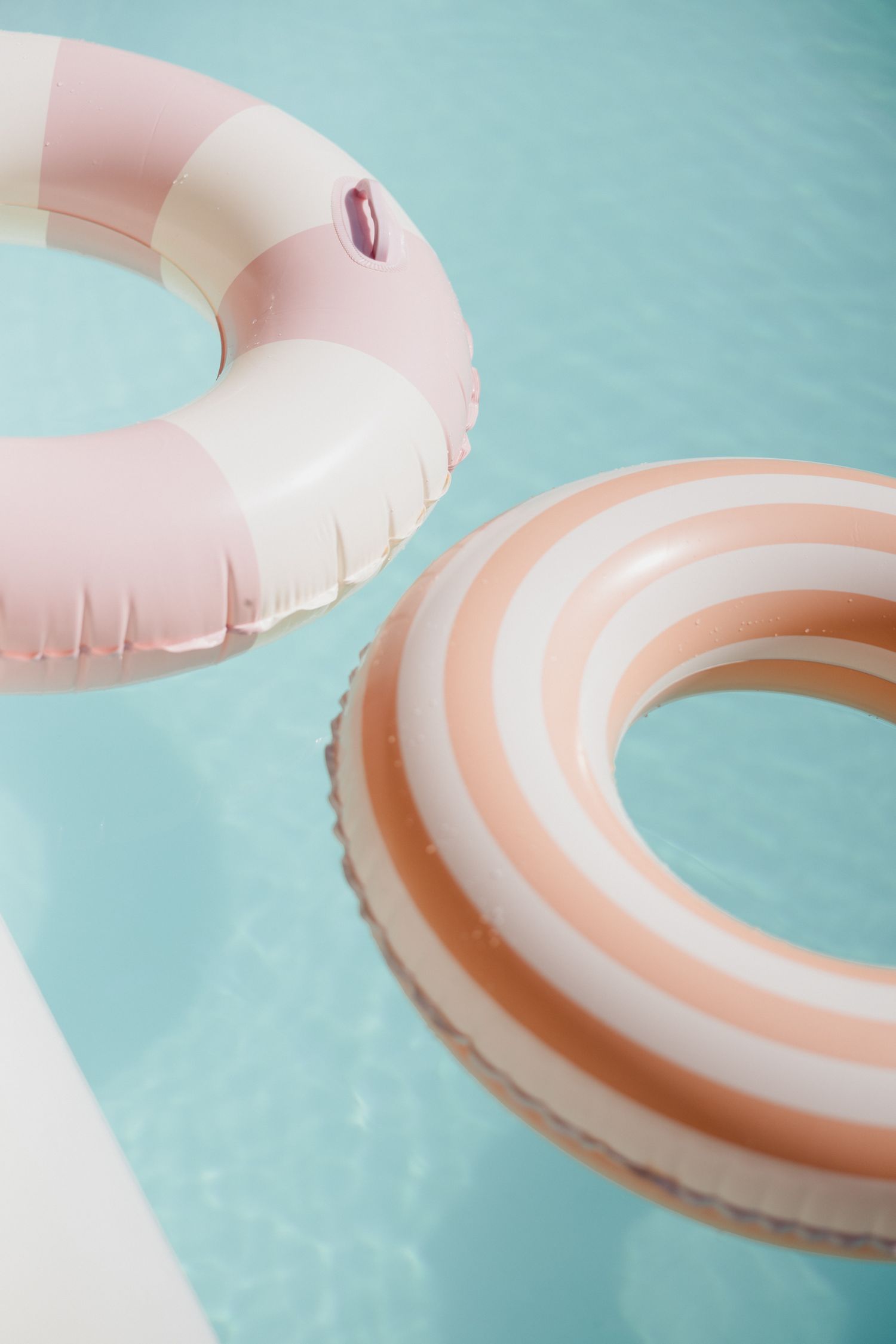Pink inflatable pool float ring on turquoise water creates a dreamy summer aesthetic.
