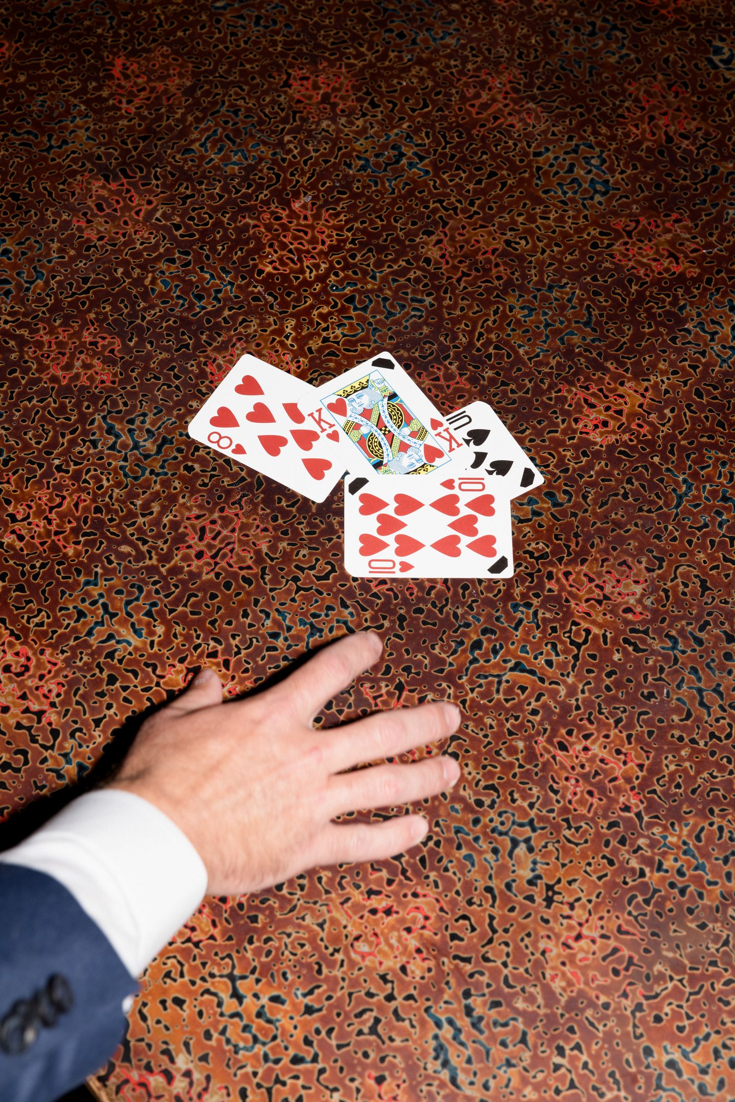 Playing cards being dealt across a textured red surface in a sequence of four connected photographs. wedding photographer france
