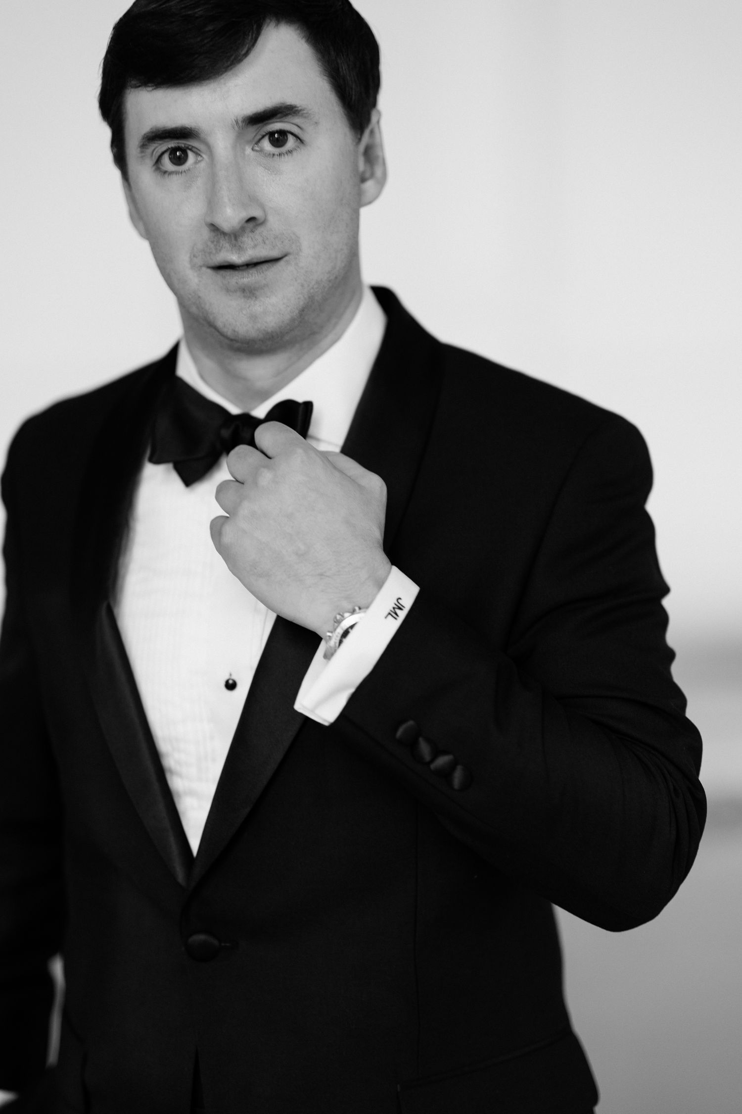 A series of black and white portraits showing a groom in a classic tuxedo making various expressions.