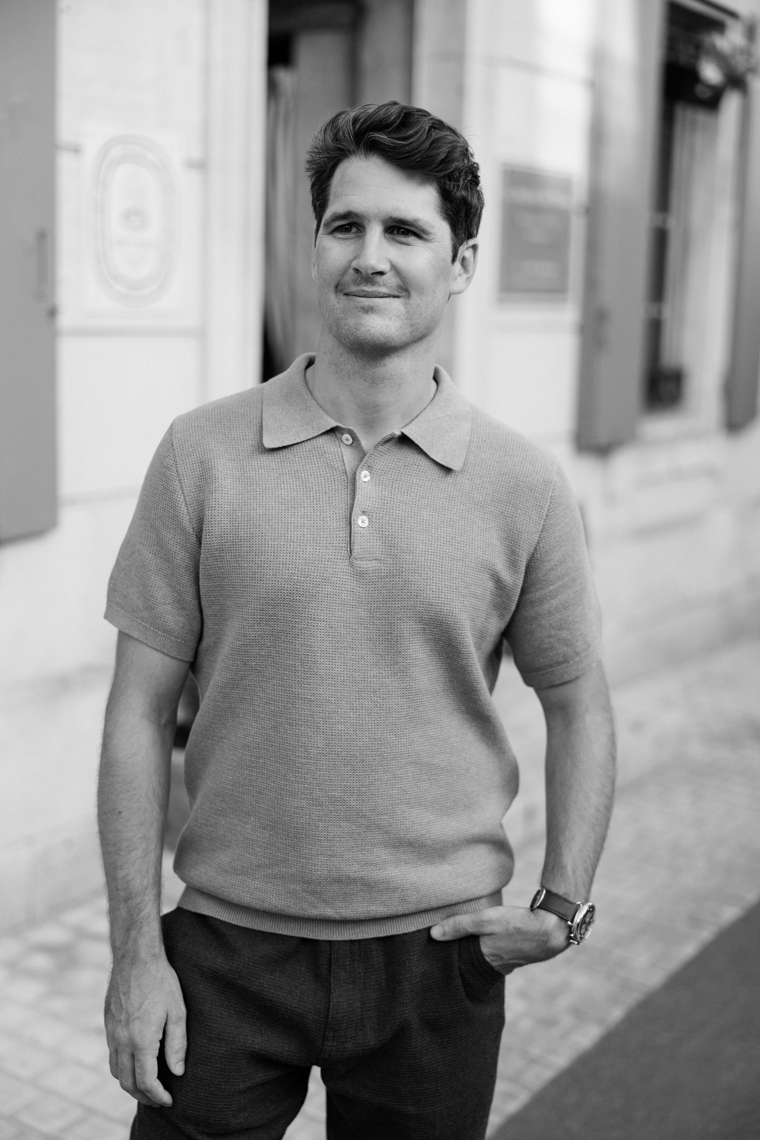 Black and white portrait of a person in a casual polo shirt standing against a light wall.