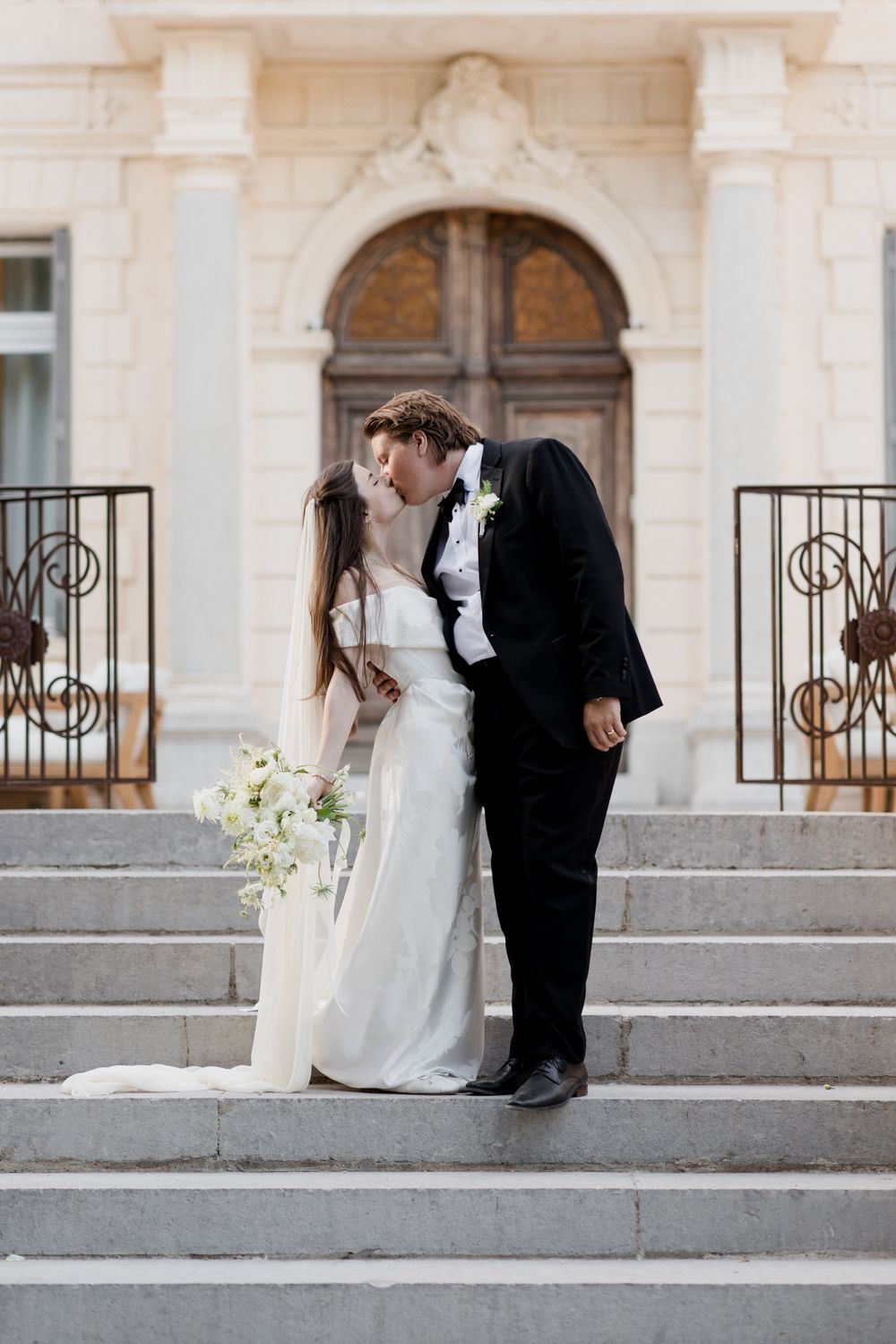 A series of romantic wedding photos showing a couple in classic formal attire embracing on elegant stone steps. Château des 3 Fontaines