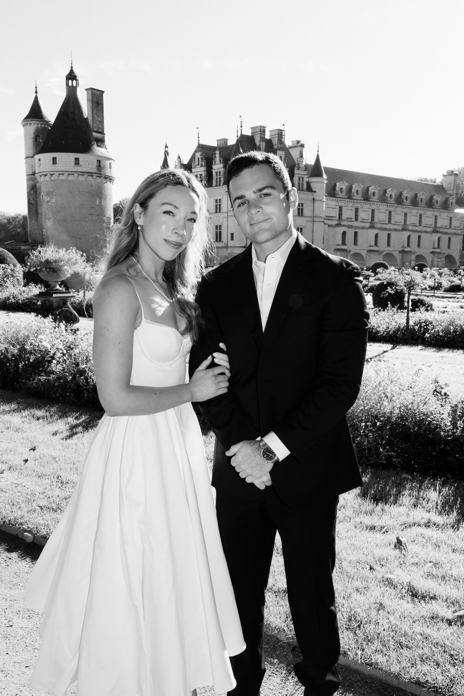 Black and white portrait of bride and groom embracing before the turrets of a French Loire Valley château.