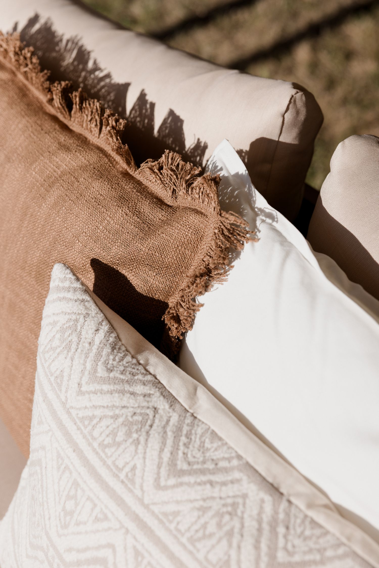 Close-up view of white and brown textiles with geometric patterns and frayed edges layered together.