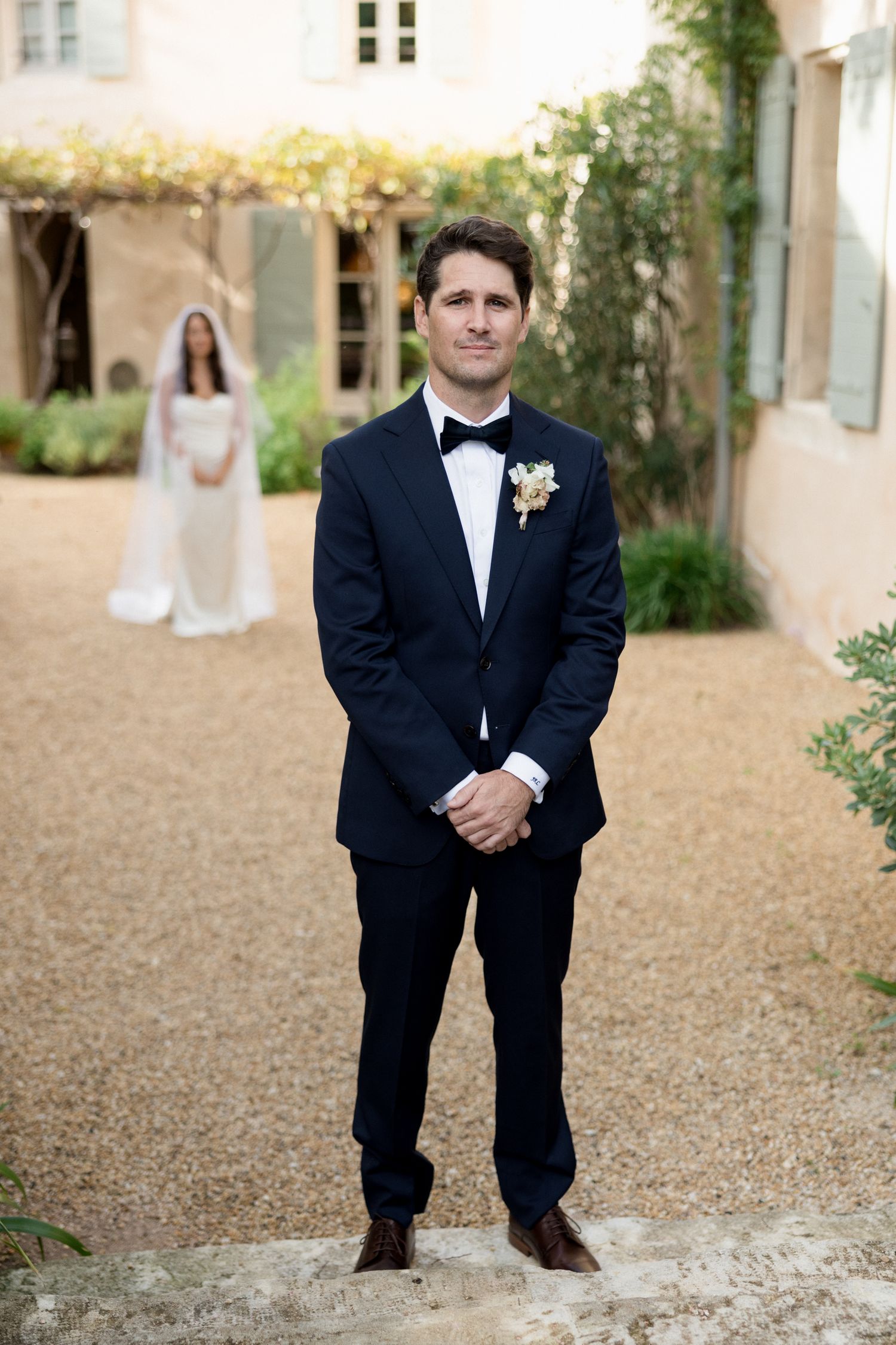 Wedding portraits taken in a rustic courtyard with gravel paths and white walls in the background.
