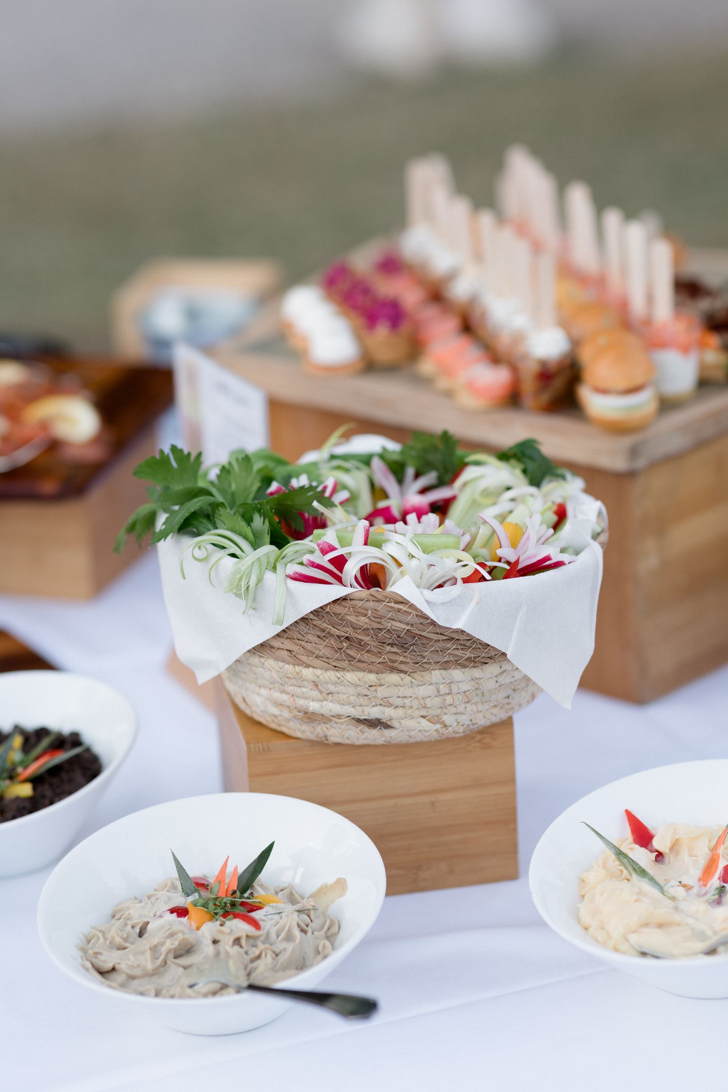 Elegant catering display featuring gourmet appetizers, sliders, and fresh salads arranged on wooden serving boards.