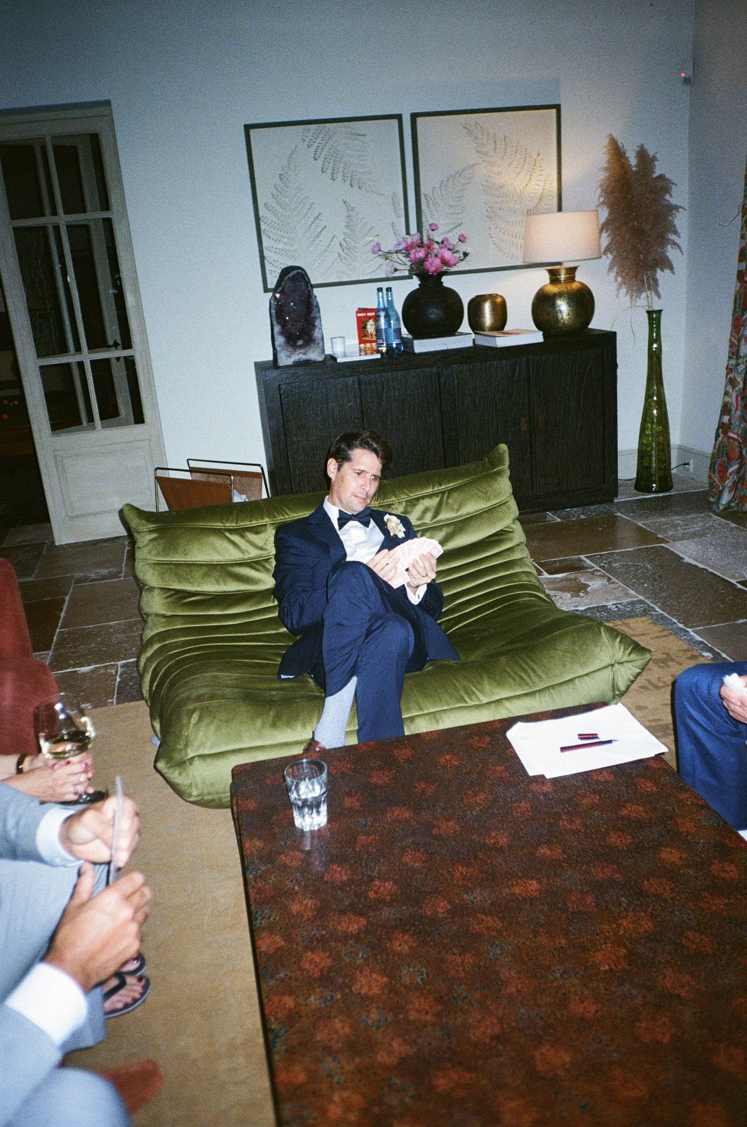 A sequence of photos showing someone progressively lying down on a green couch in a room with a patterned carpet.