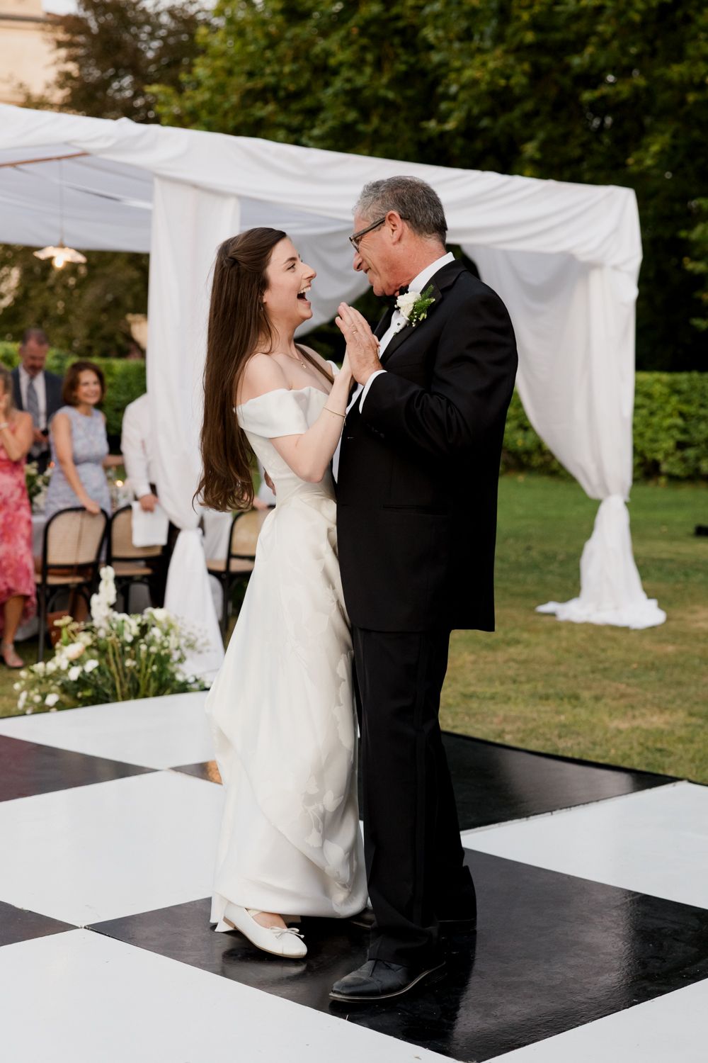 Wedding ceremony moment with white draping decor and elegant black dance floor.