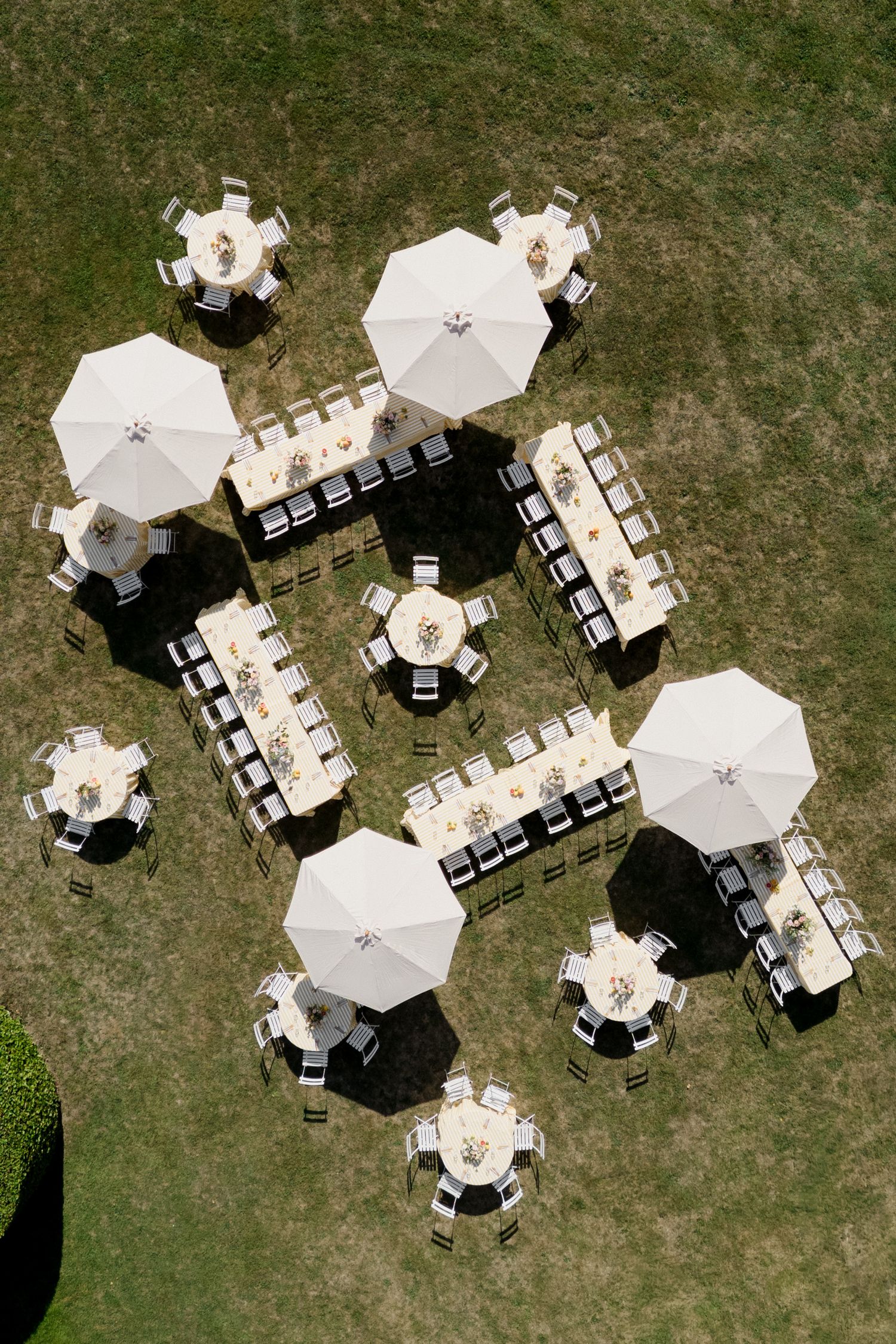 Aerial view of outdoor event setup with white umbrellas and tables arranged on grass lawn. Pool party loire valley