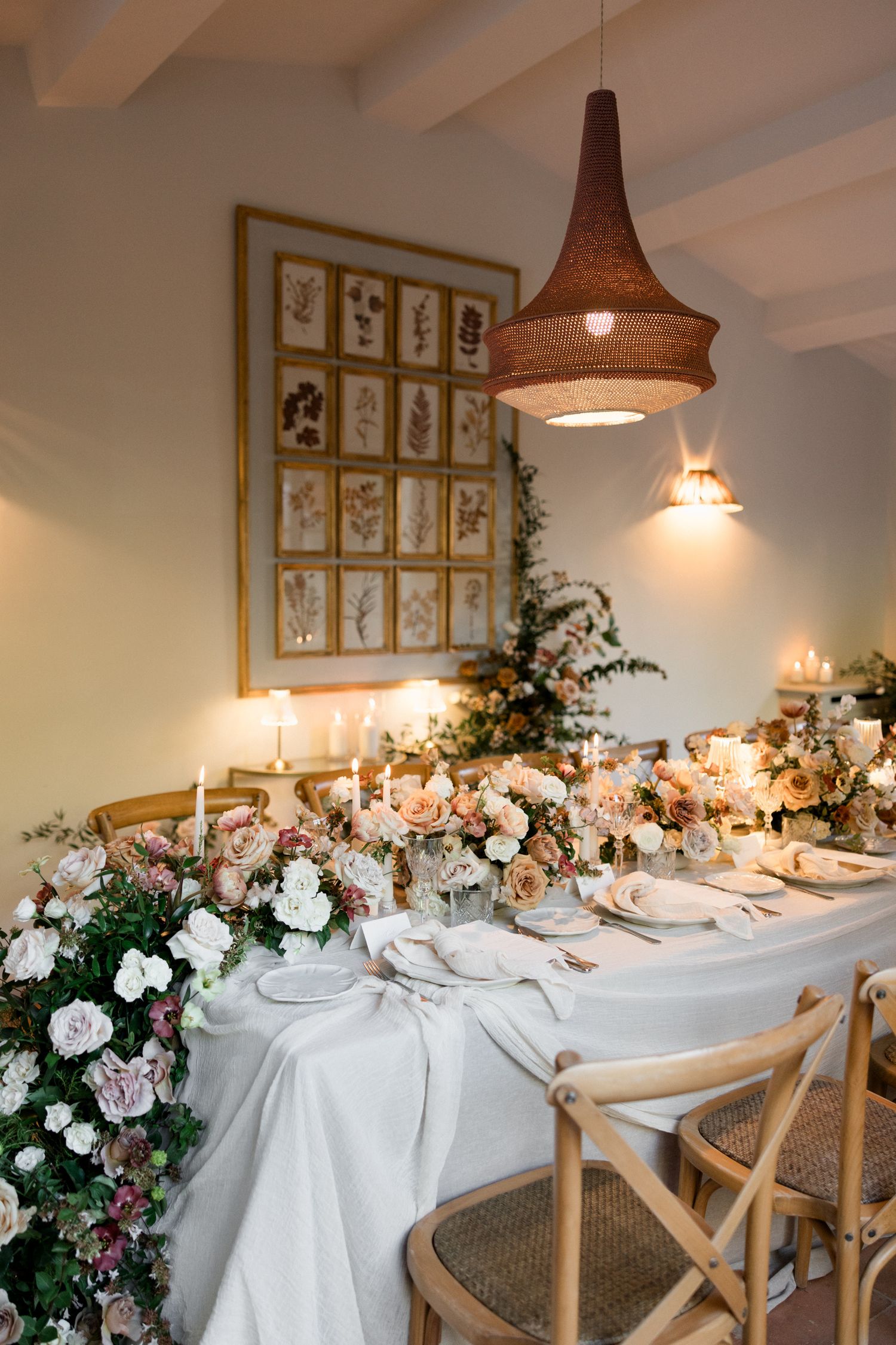 Elegant dining table setup with white linens, woven pendant lights, and floral arrangements in a rustic restaurant setting. wedding photogra