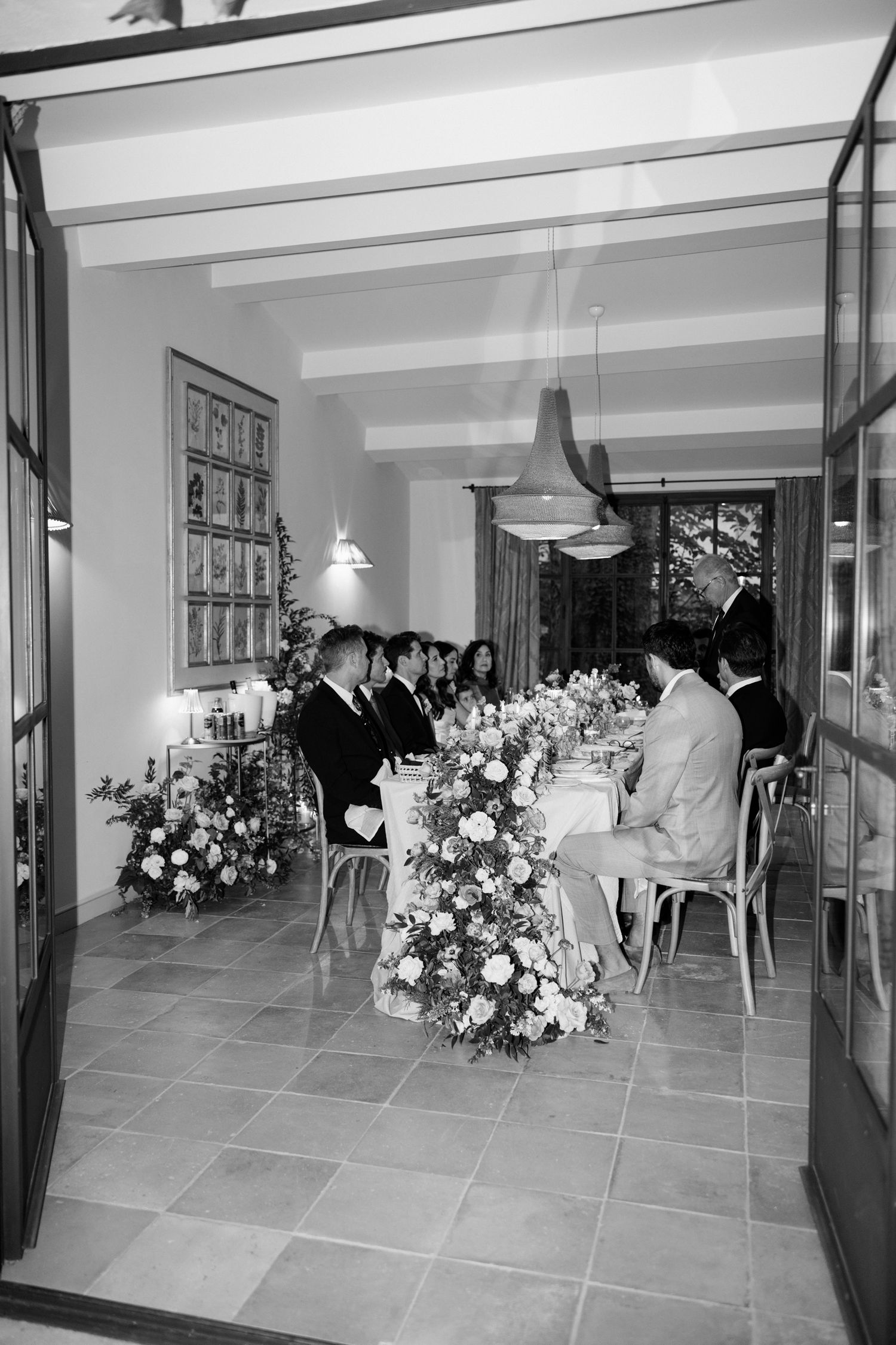 Black and white panoramic view of an elegant event space with floral arrangements and modern interior design elements.