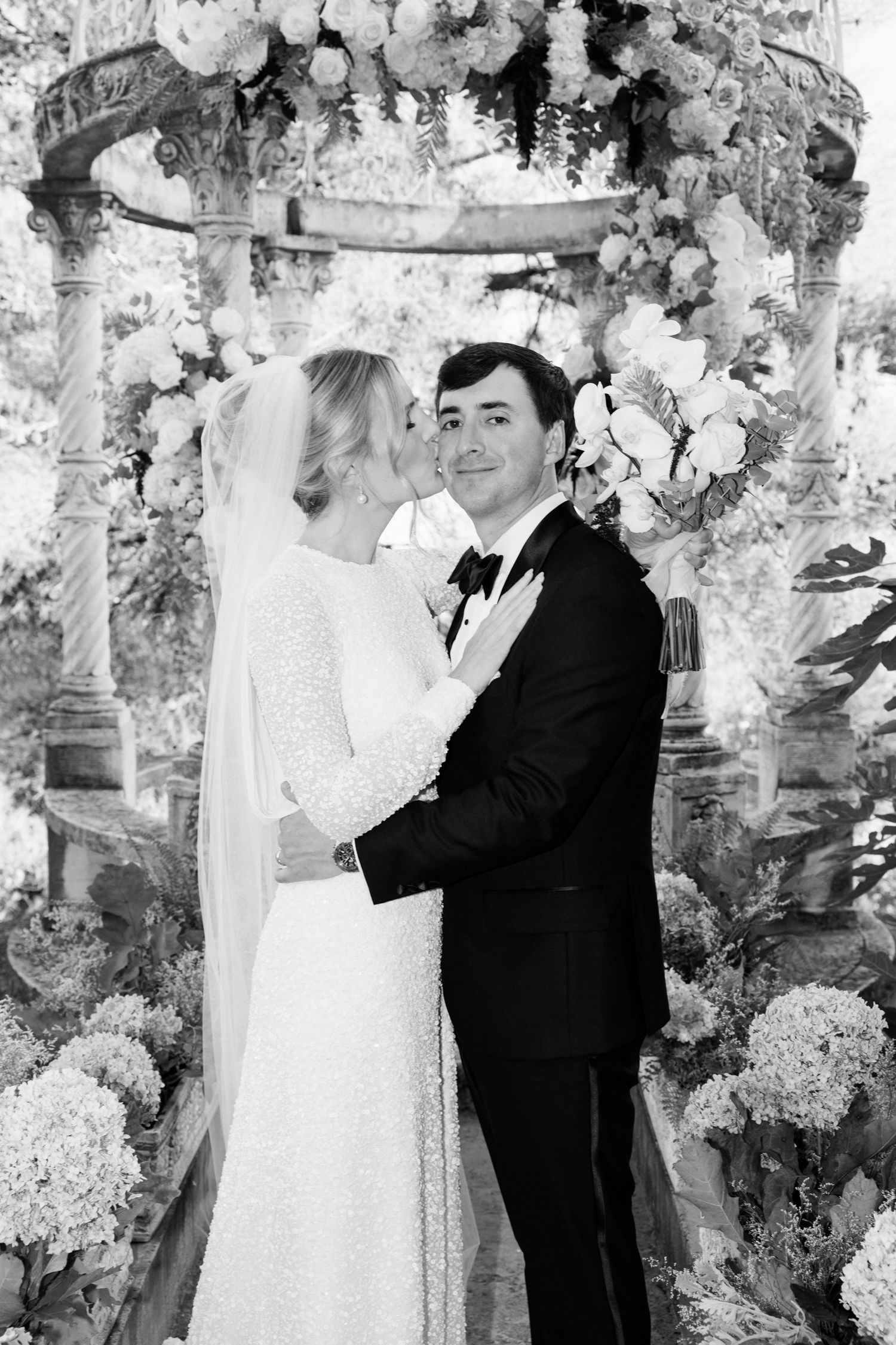 Black and white wedding photos show couple embracing in romantic garden setting with floral decorations. Intimate wedding french riviera