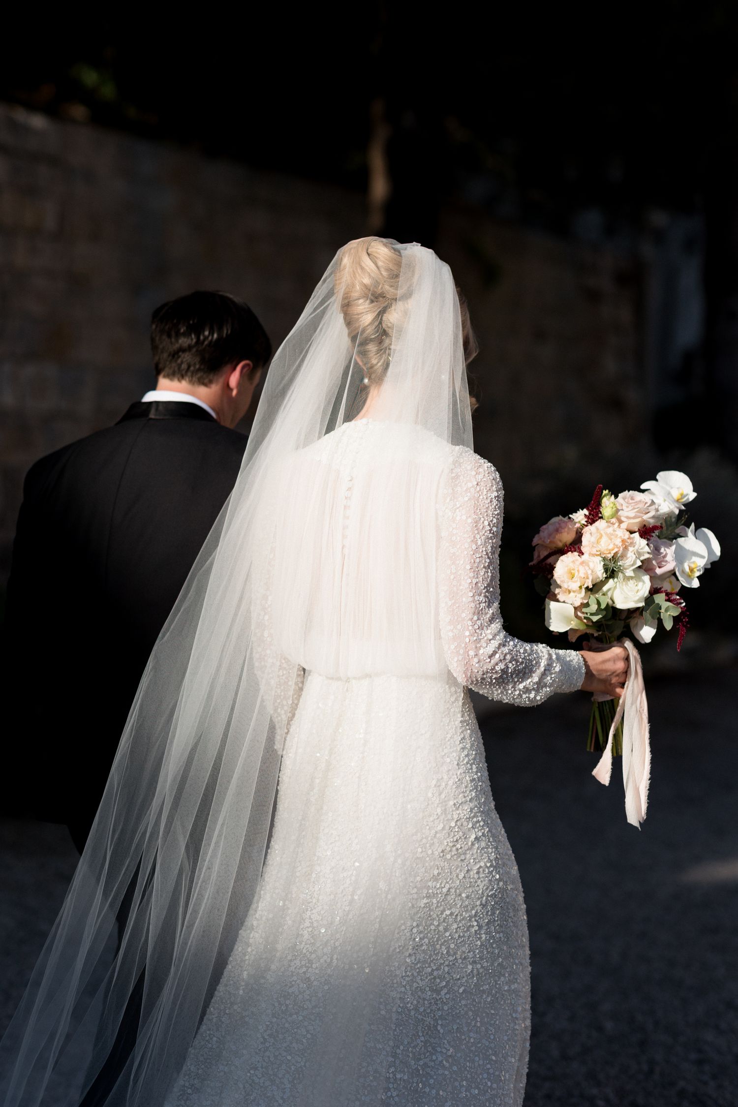 A bride in a white lace wedding dress and long veil stands in a series of artistic silhouetted photos. editorial wedding photographer france
