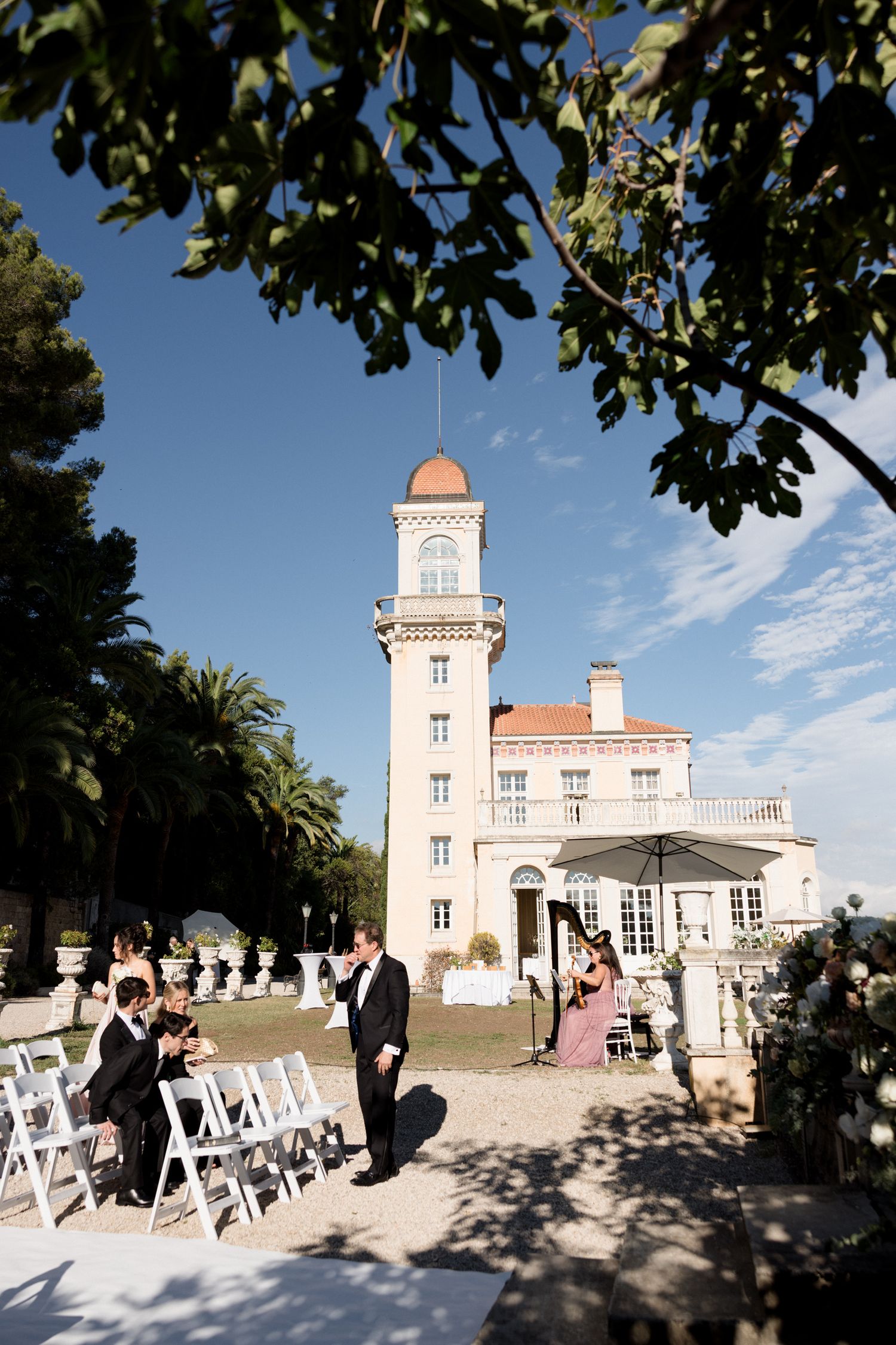 White chairs arranged for an outdoor wedding ceremony at a beautiful pink and white coastal mansion venue.