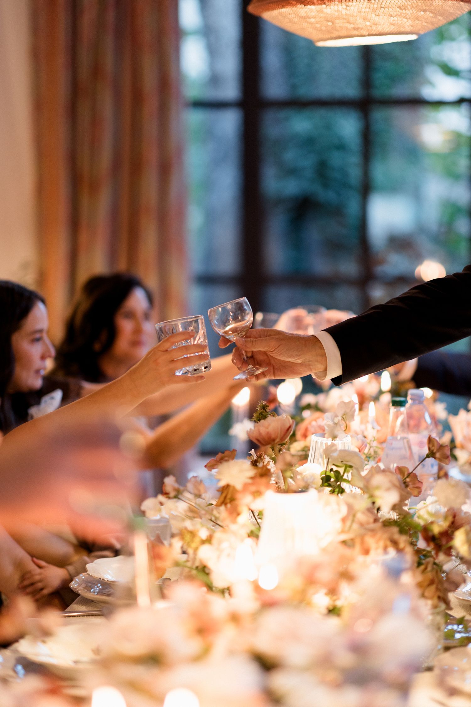 Elegant dining table set with glowing candlelight and floral arrangements at an evening reception.