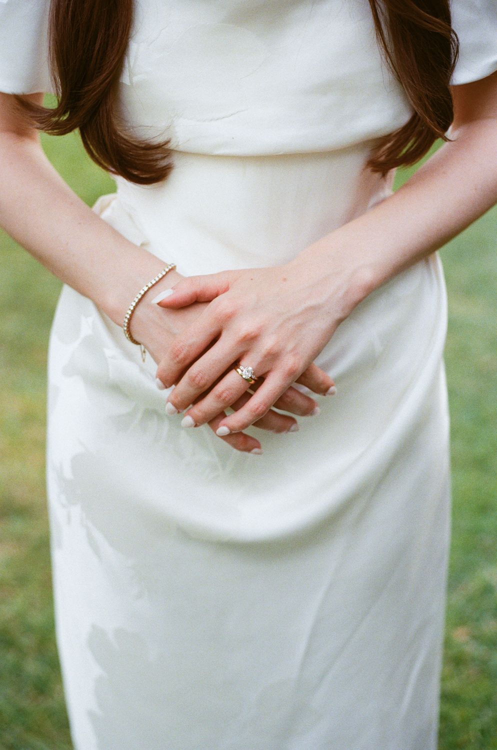 Close-up sequence of hands resting against white fabric shows wedding ring details. Wedding on film