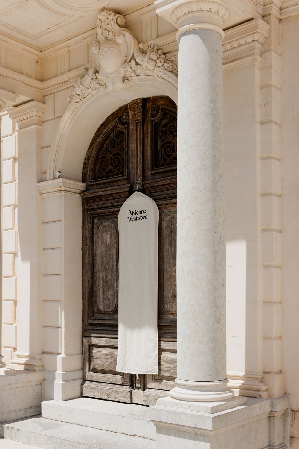 Classical architecture interior with white columns and dark wooden doors in a light-filled colonnade.