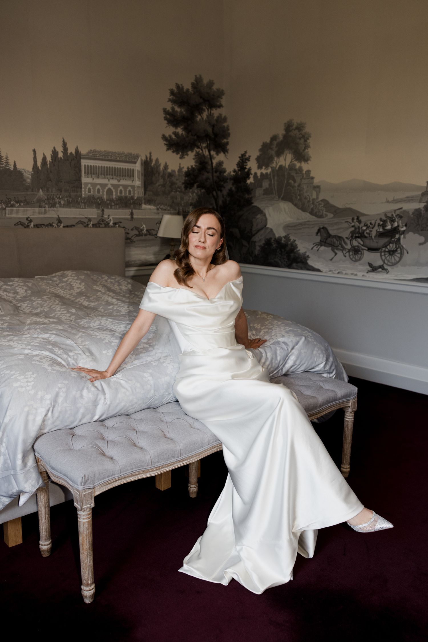 A white wedding dress is dramatically displayed across a vintage-style daybed against a dark background in a photo series. Paris wedding
