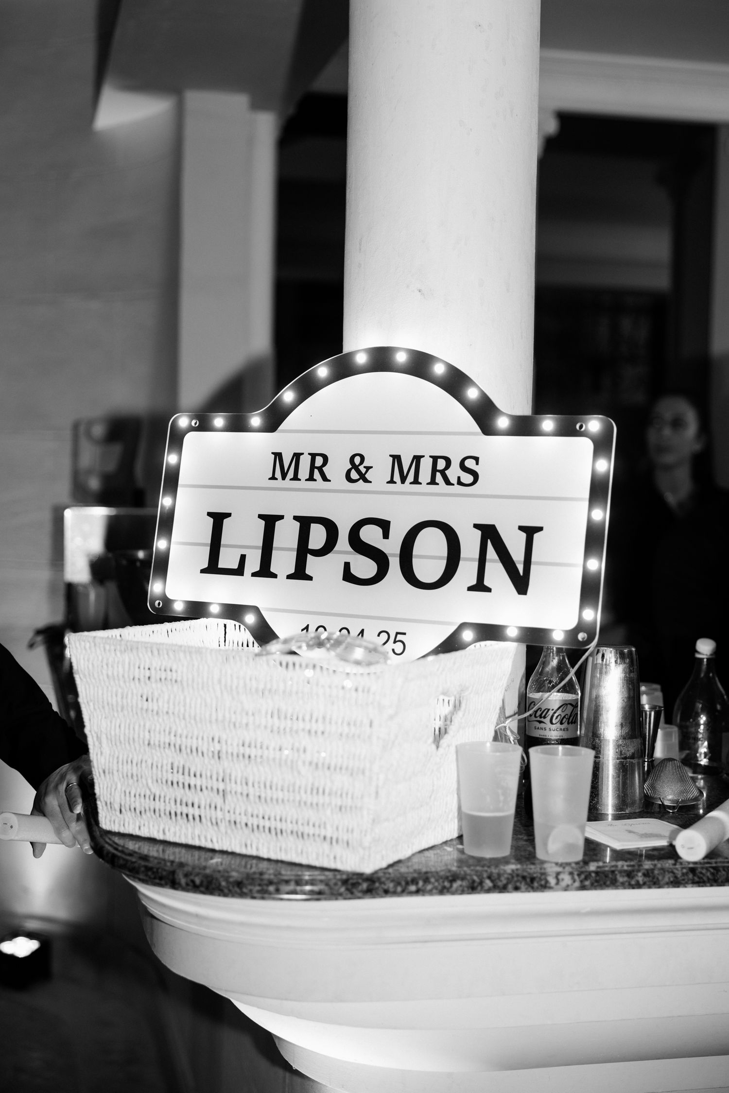 Black and white photo series of wedding reception table settings with 'Mr & Mrs Lipson' name cards and decorative baskets.