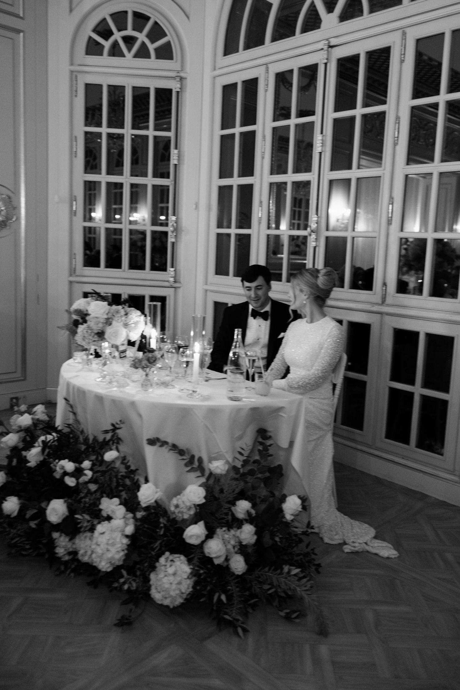 Elegant wedding reception hall with arched windows and white floral arrangements adorning dining tables. The Lane wedding