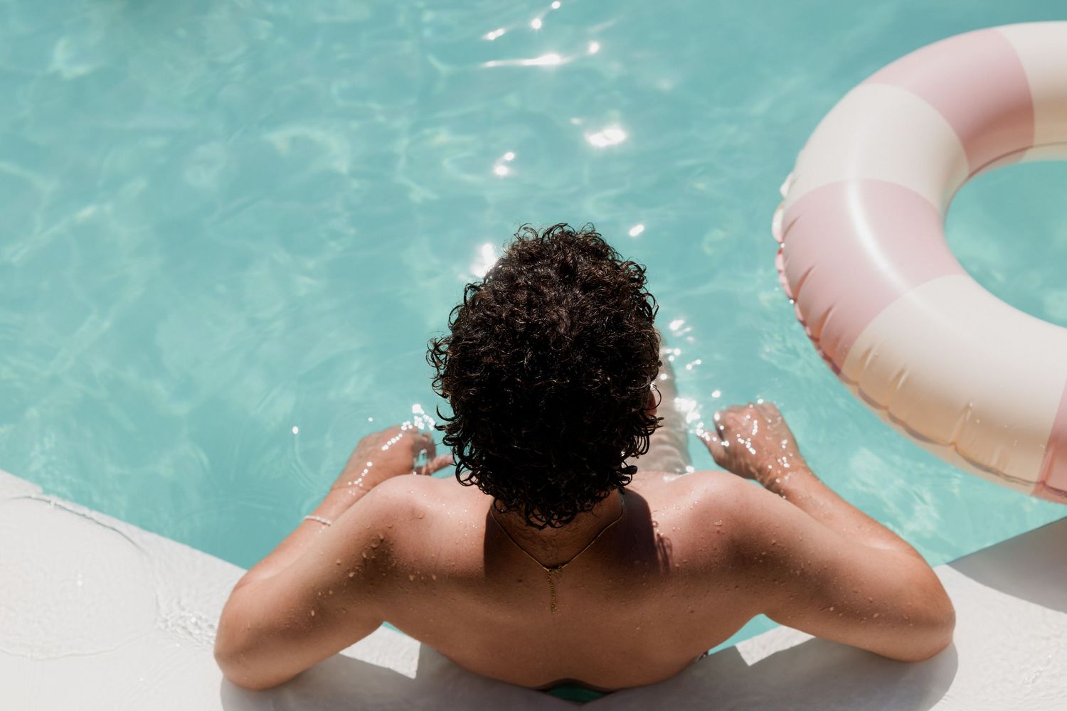 Person swimming underwater in a pool with a pink inflatable ring floating above. Brunch loire valley