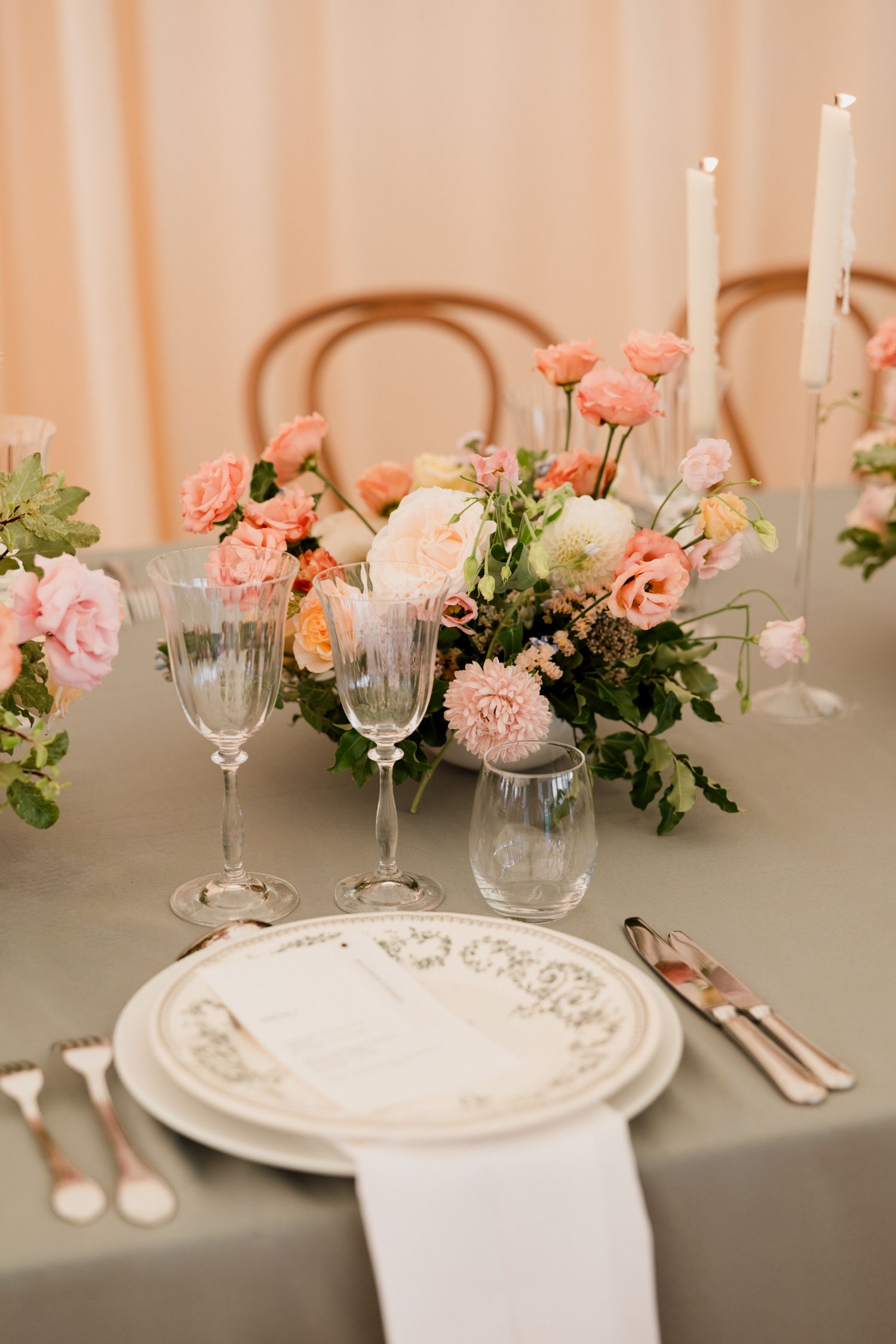 Elegant wedding table setting with pink roses, white plates, crystal glasses and candlesticks on a neutral tablecloth. Paris wedding photogr