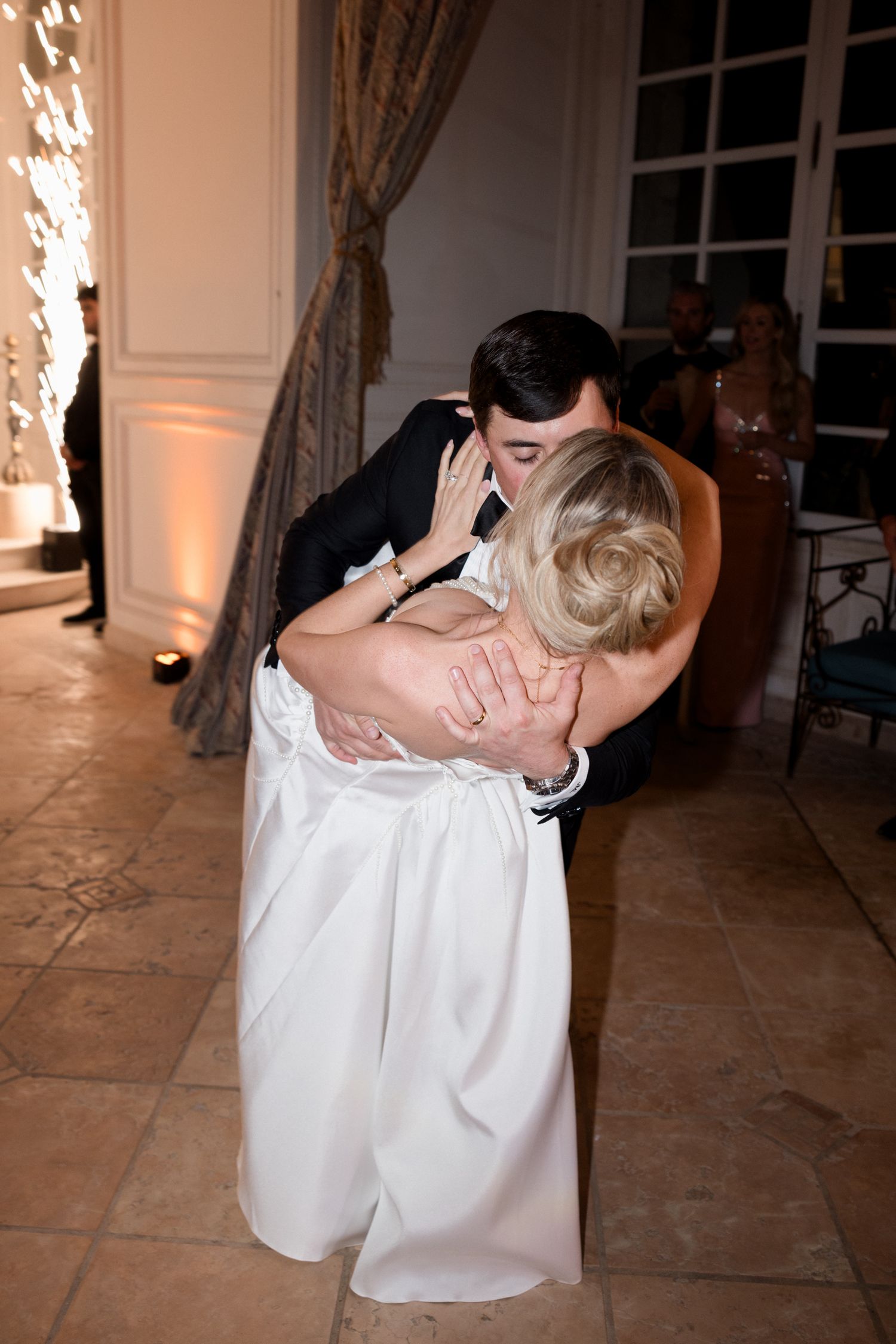 A romantic wedding dance moment shows a couple embracing on the dance floor with elegant decor in the background.