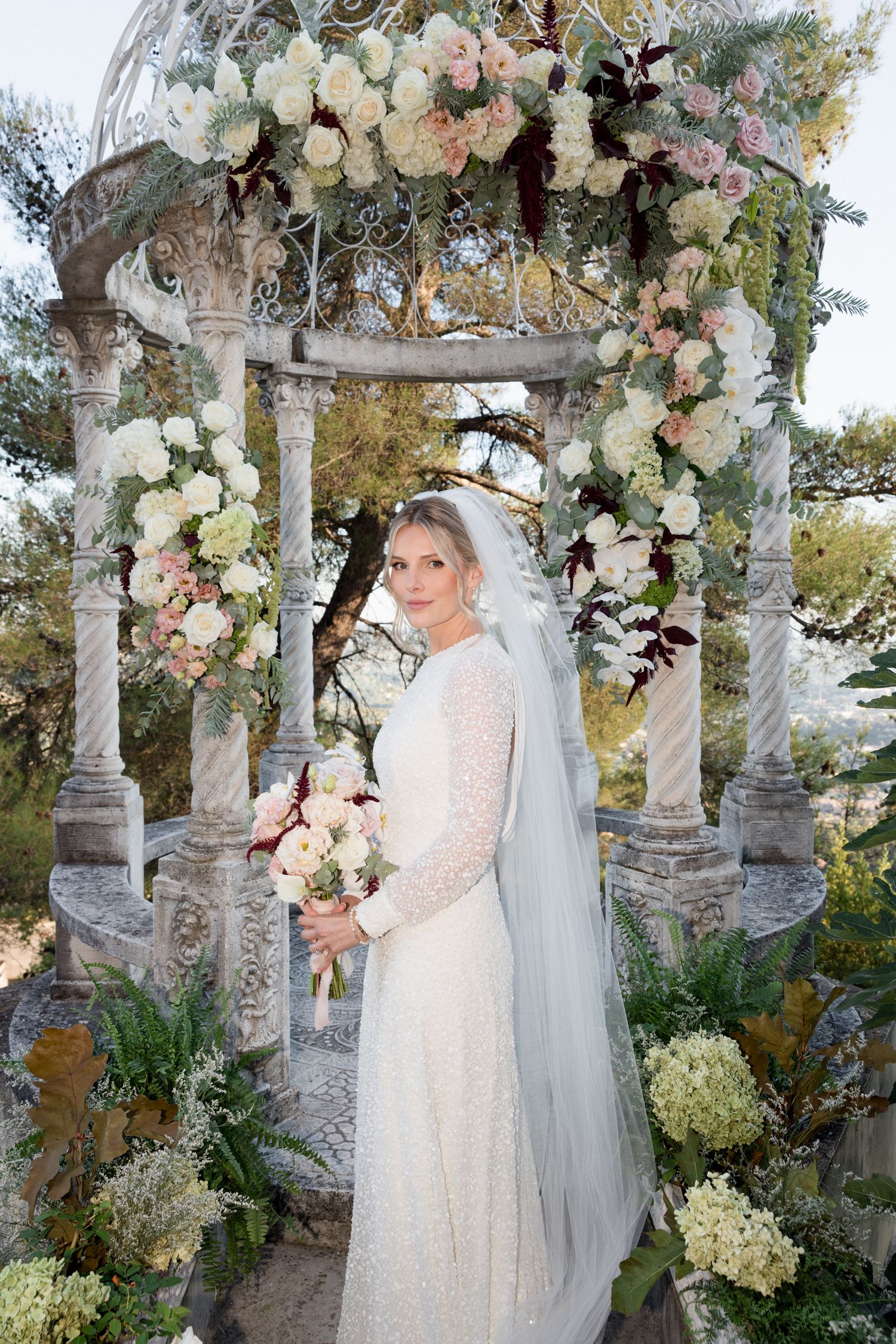 Elegant bridal scene under a floral-adorned stone gazebo with white and blush roses and cascading greenery. Intimate wedding french riviera