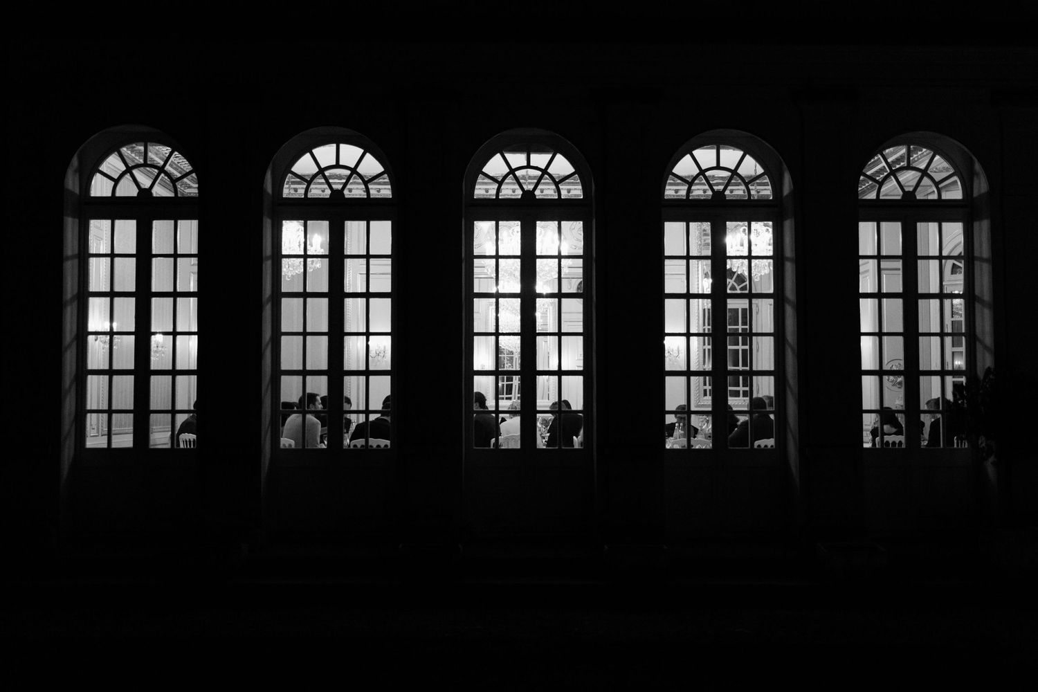 Silhouetted windows in a dark building create a dramatic architectural pattern against a black background.
