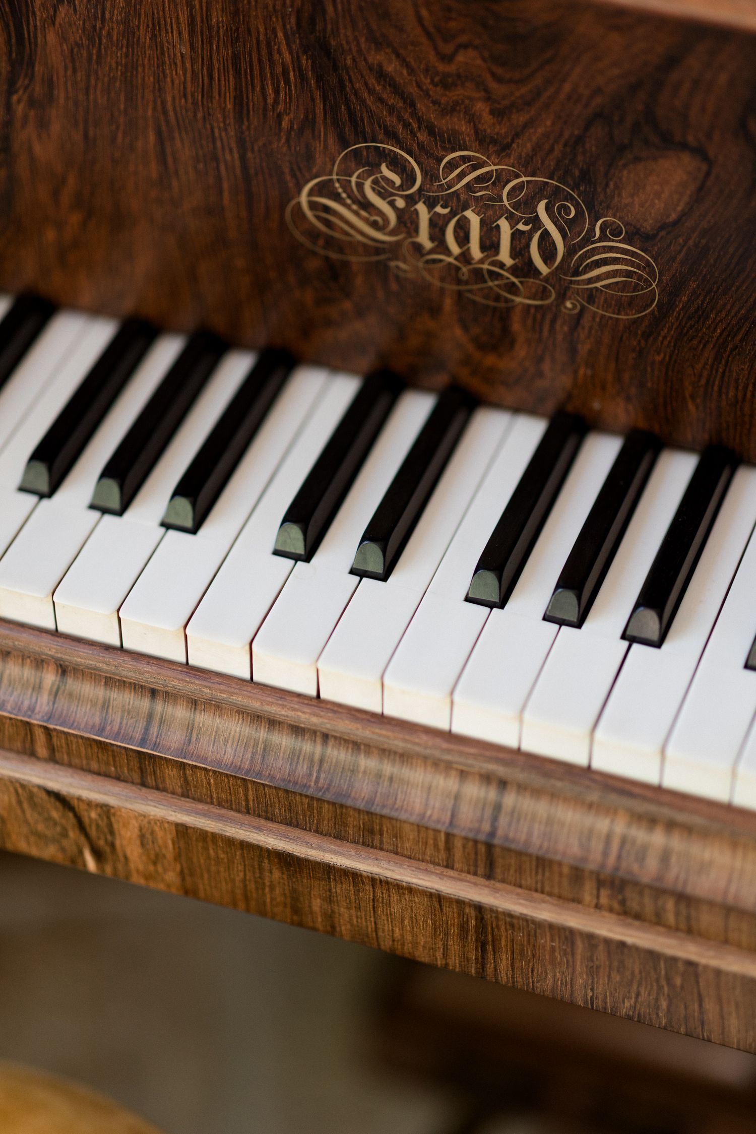 Close-up view of vintage piano keys showing white and black keys against dark wood grain texture.