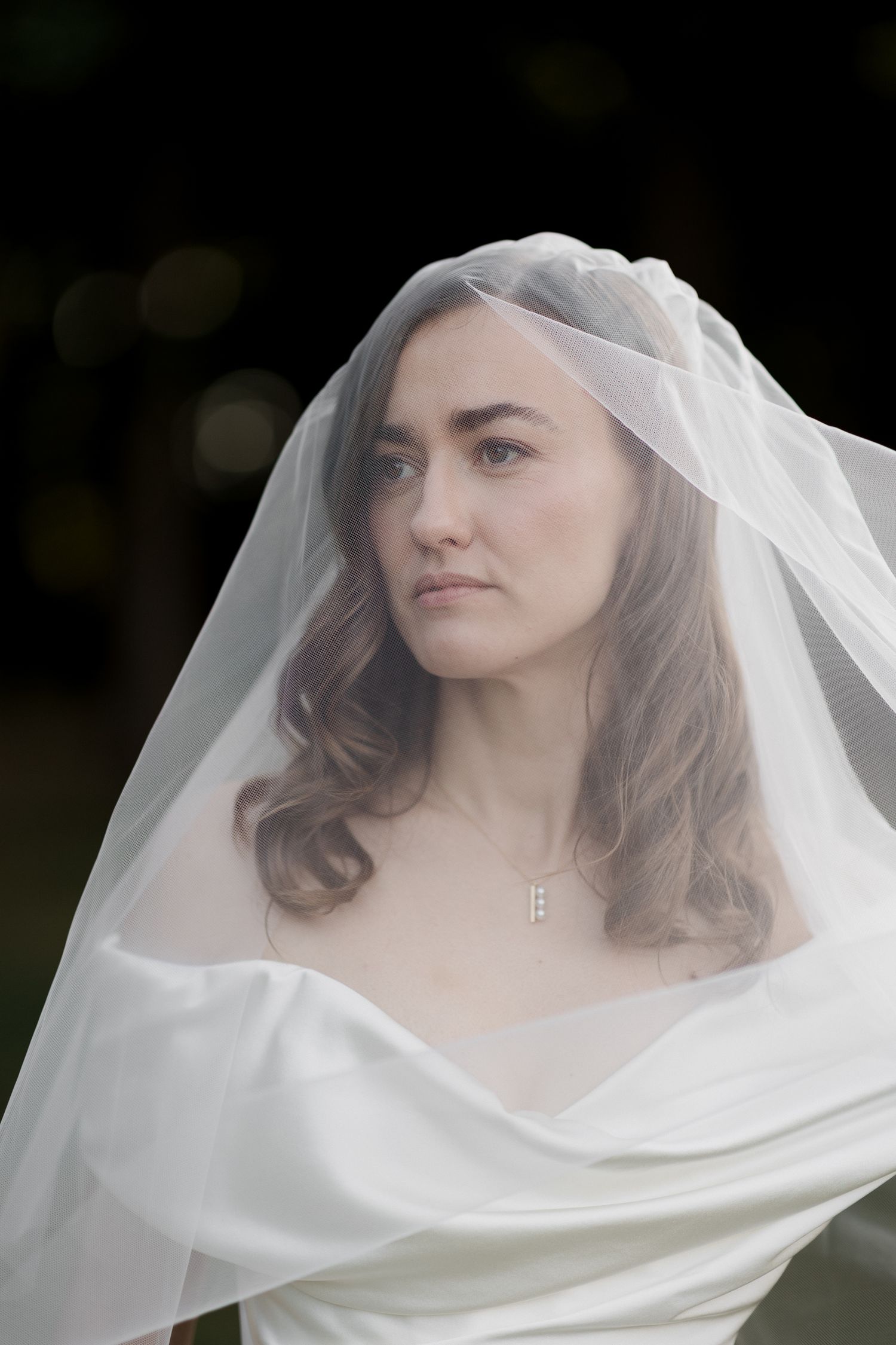 A bride wearing a flowing white veil poses in a series of ethereal outdoor portraits. Luxury wedding france
