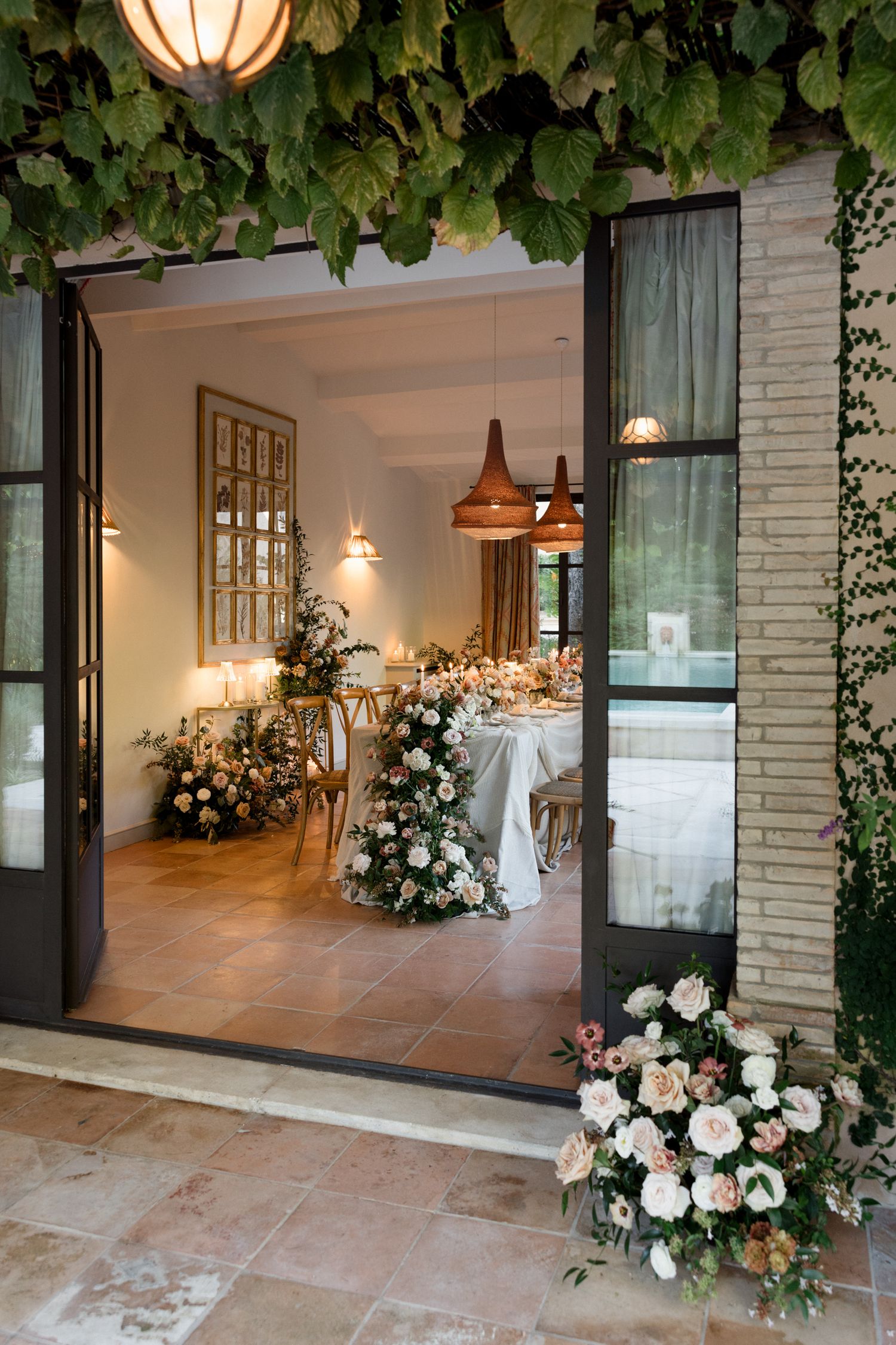 Elegant wedding venue entrance decorated with lush white floral arrangements and illuminated by warm pendant lights.