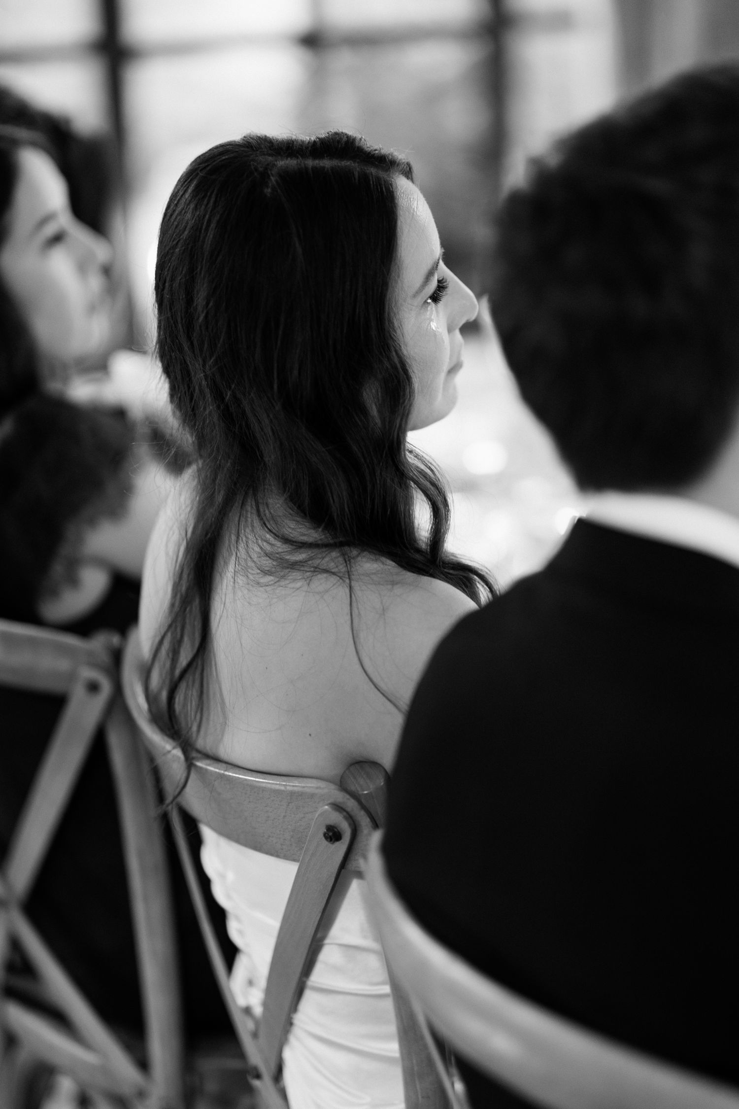 Candid black and white photo showing guests in formal attire at an elegant reception or celebration.