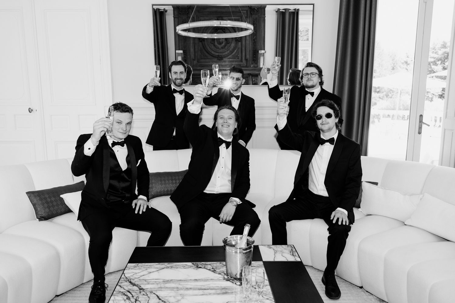 A creative split-panel photo of groomsmen in black tuxedos striking fun poses against a white backdrop. Photographe mariage Tours