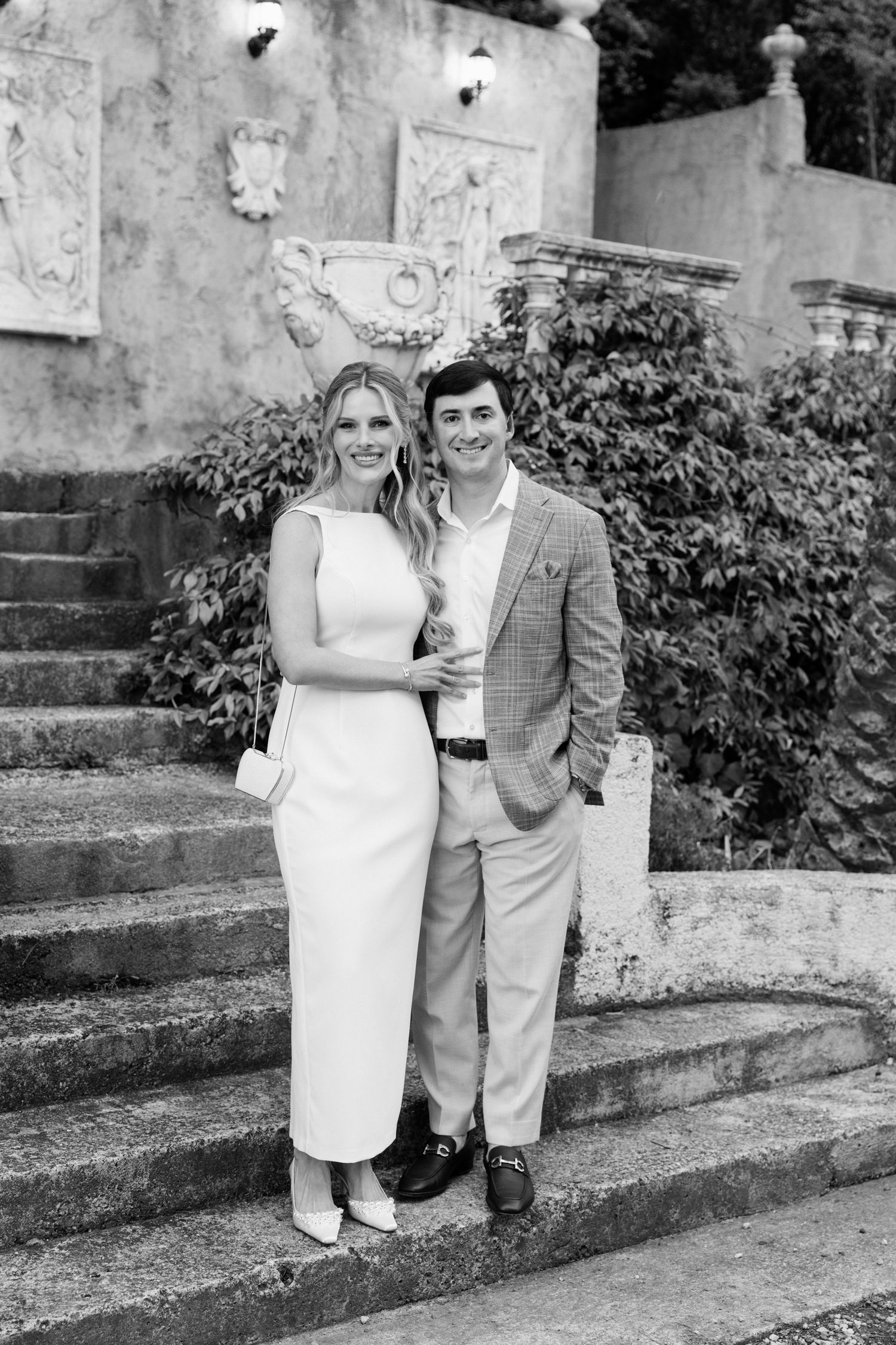 A couple poses together on stone steps outdoors in black and white photos showing four similar poses.