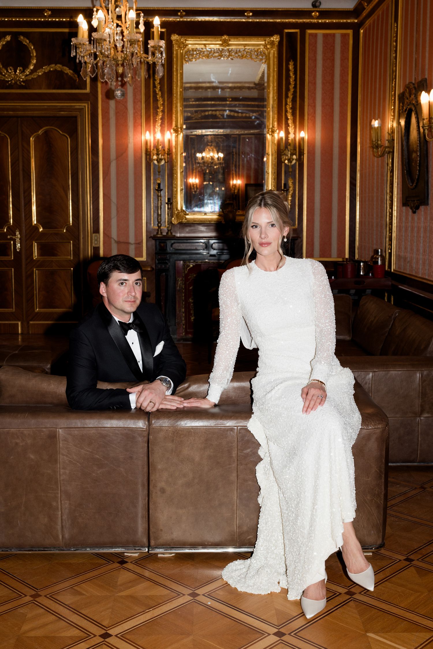 Elegant figures pose in a luxurious ballroom with ornate chandeliers and golden decor. french riviera wedding