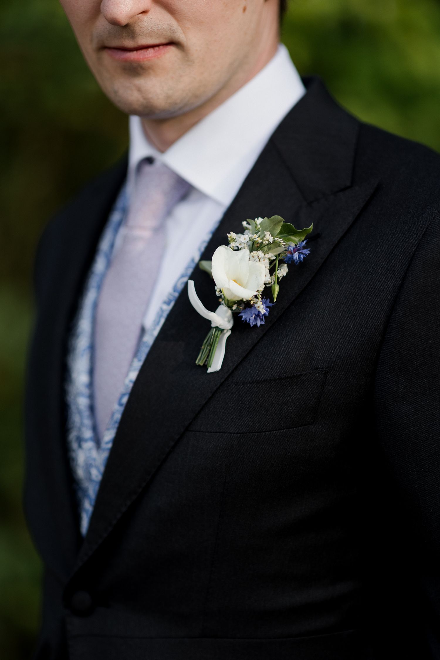 A series of close-up shots showing a groom's black suit jacket with a white rose boutonniere and light pink tie.