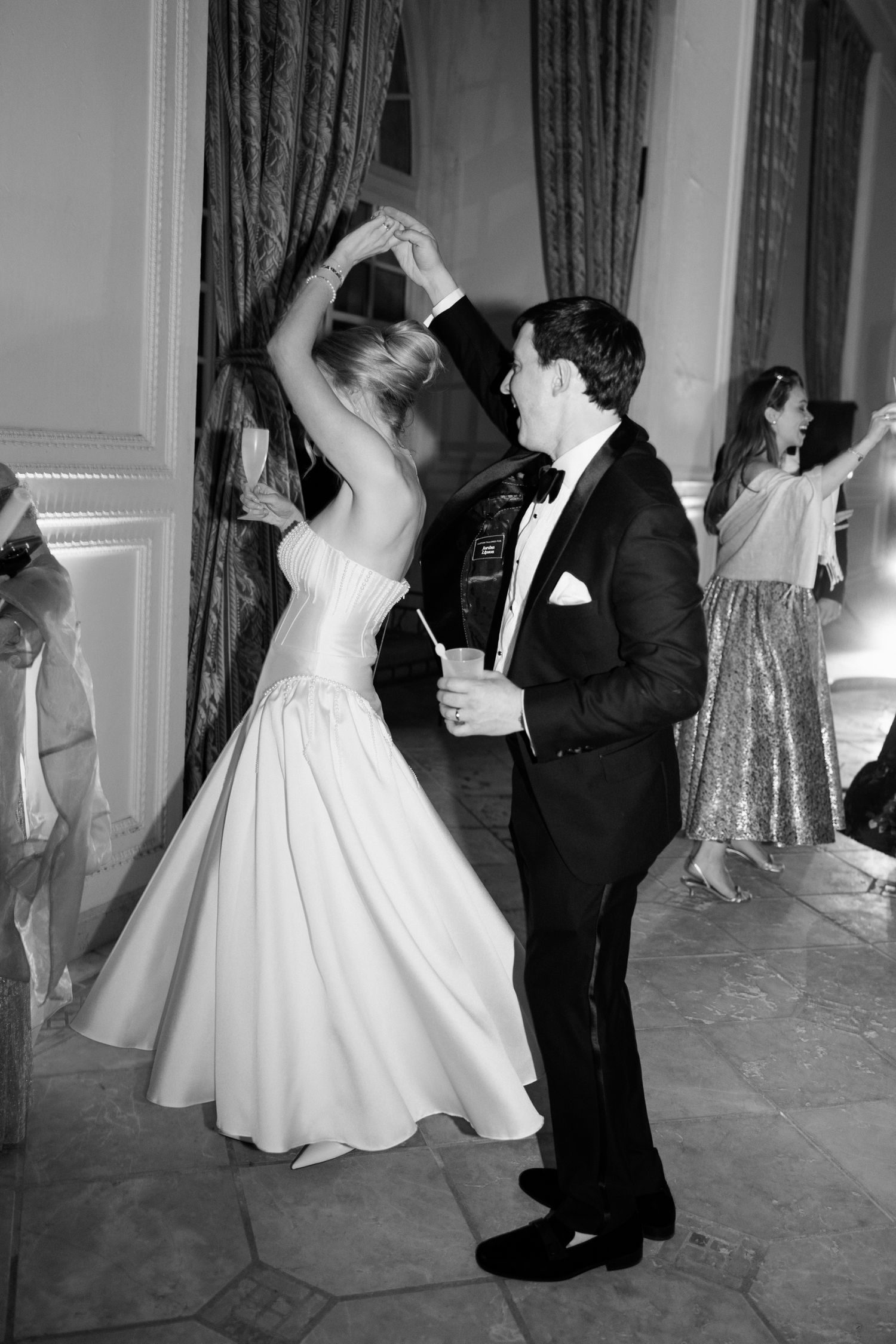 A couple dancing at an elegant wedding reception, with the bride in a white gown and groom in a tuxedo.
