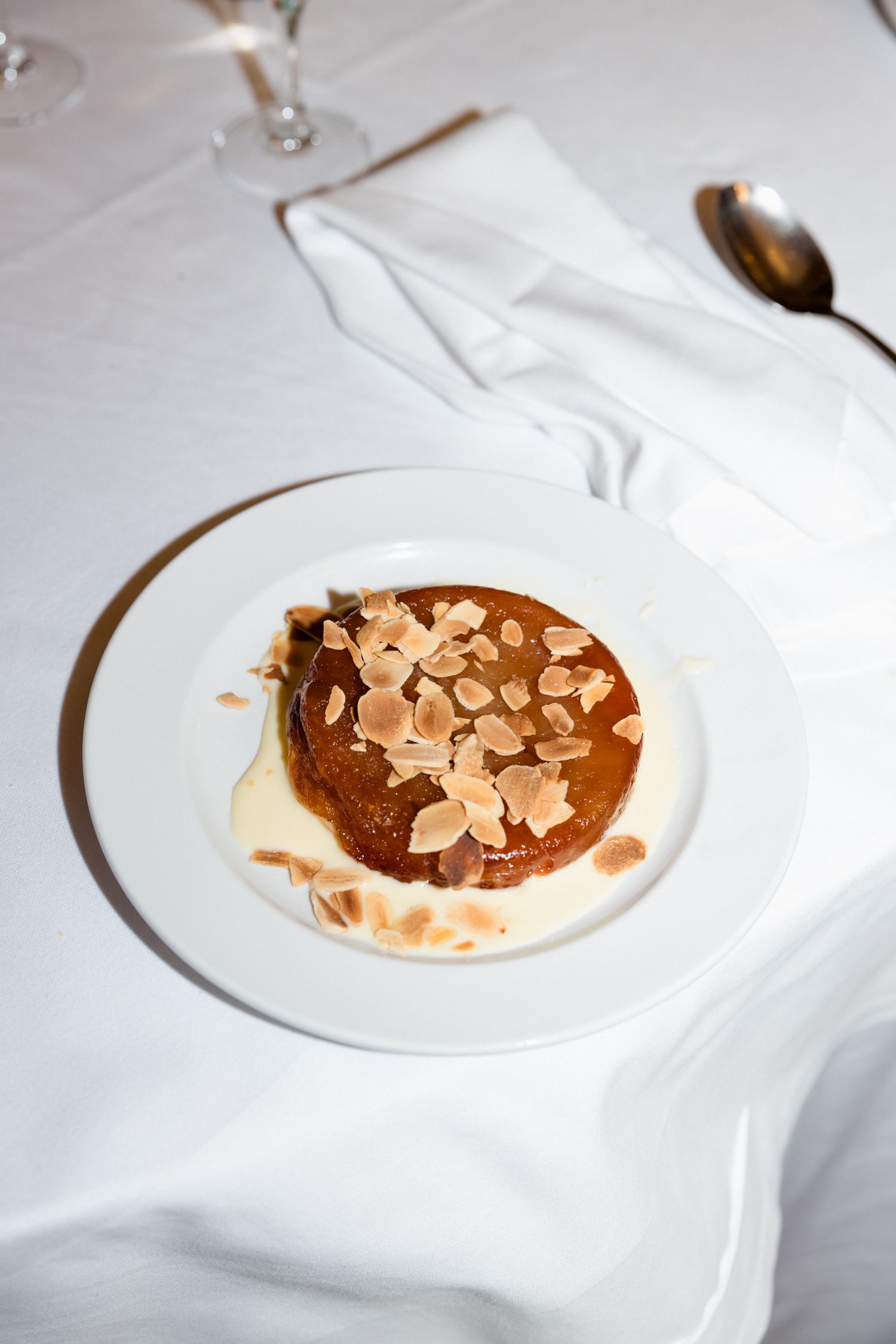 A sequence of plated desserts showing the progression of chocolate and almond garnish being added to a white dish.