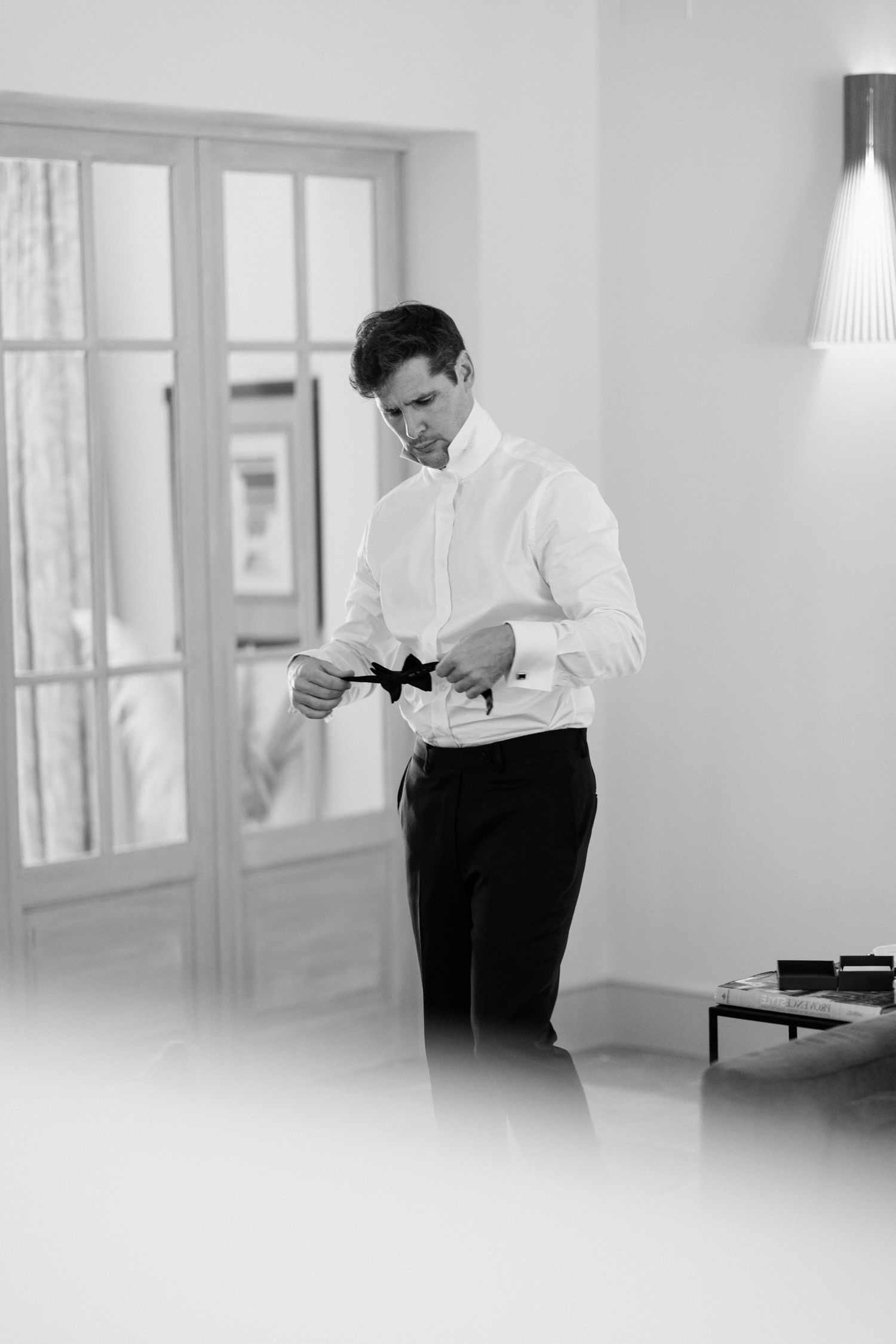 Black and white photo series showing a person in white shirt and dark pants standing in a bright minimalist room. Editorial wedding france