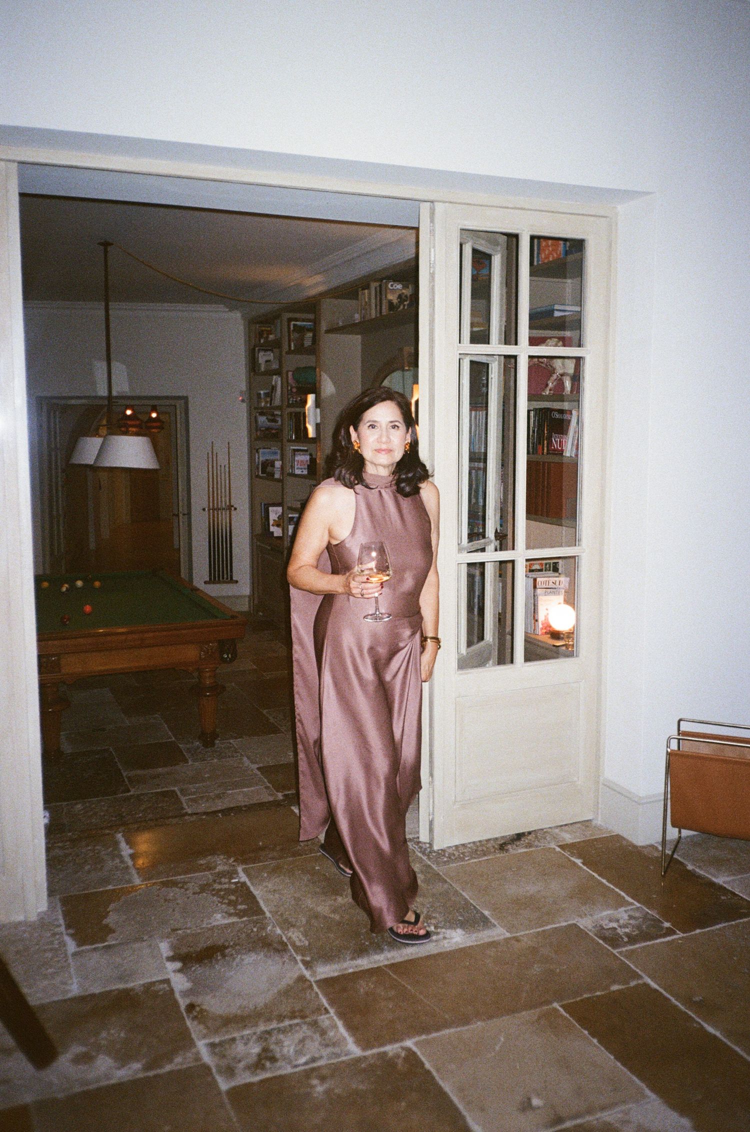 Four sequential photos showing someone in a mauve dress walking through a dimly lit stone-floored hallway.