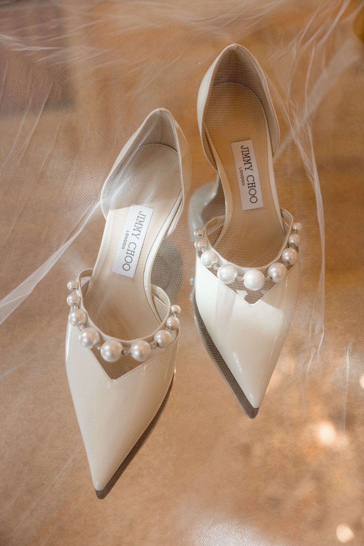 Elegant white pointed-toe slingback heels with pearl embellishments shown from multiple angles on reflective surface. destination wedding fr