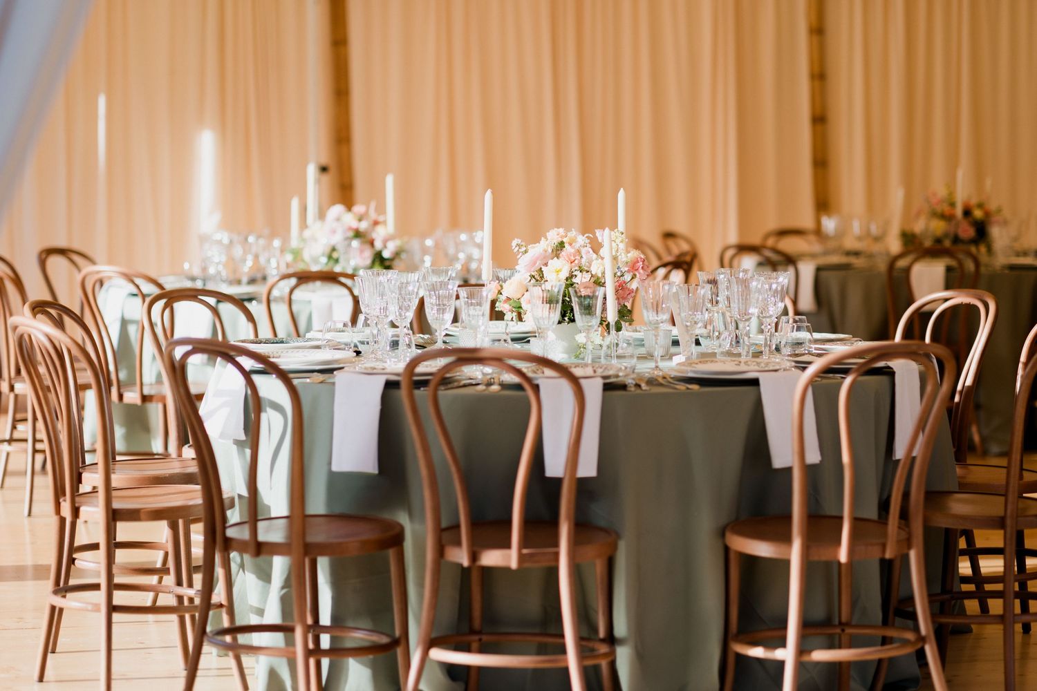 An elegant wedding reception venue with round tables, bentwood chairs, and soft lighting creating a romantic atmosphere.Luxury wedding Tours