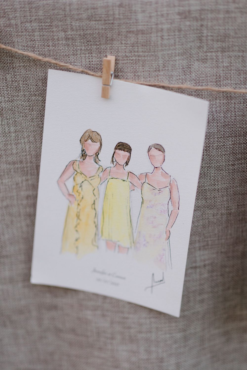 A series of delicate watercolor sketches of figures in yellow and pink dresses hung by wooden clothespins. Aurora Artiste