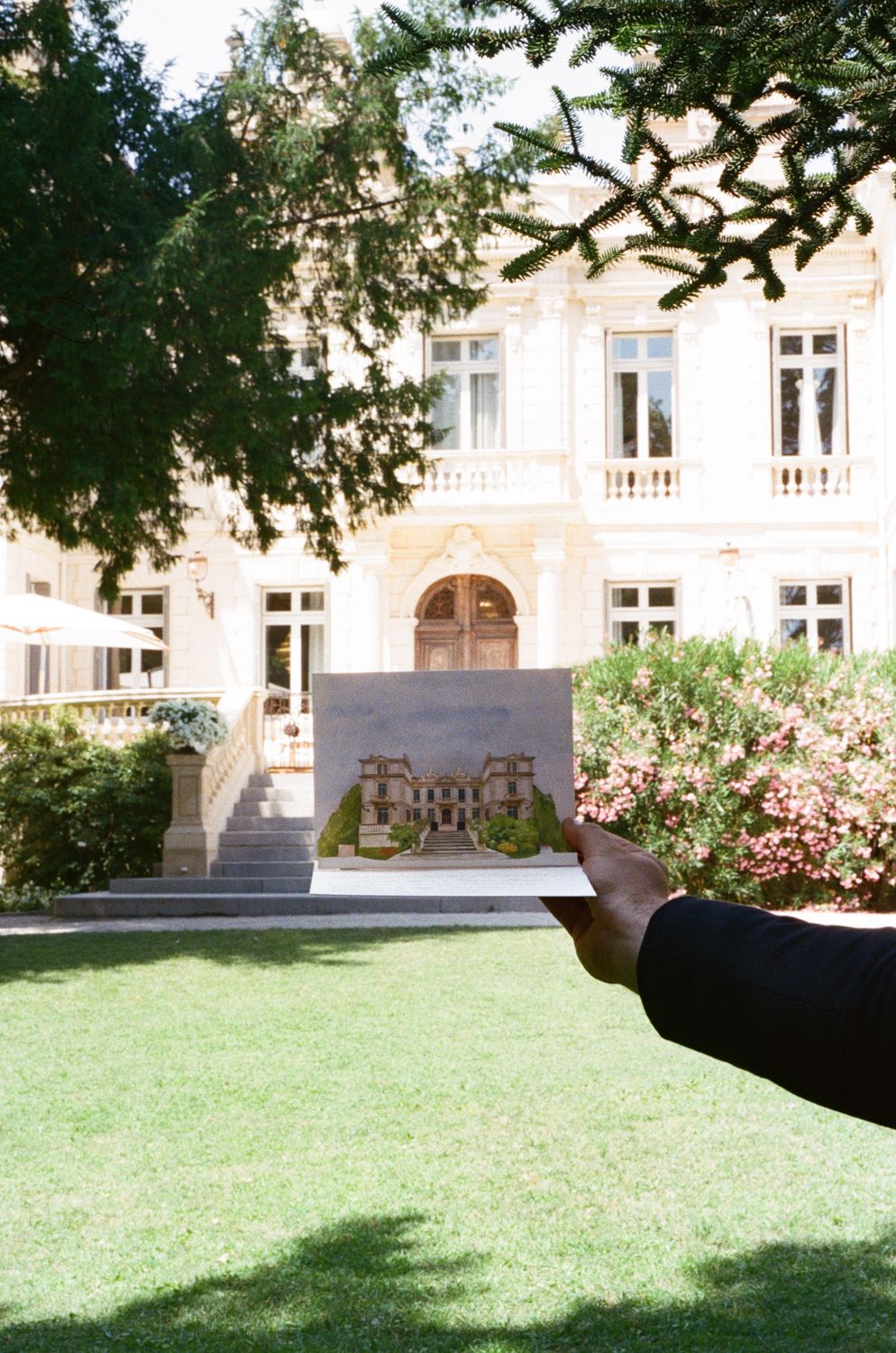 A series of connected photos showing a sunlit lawn area beside a historic stone building with arched windows.