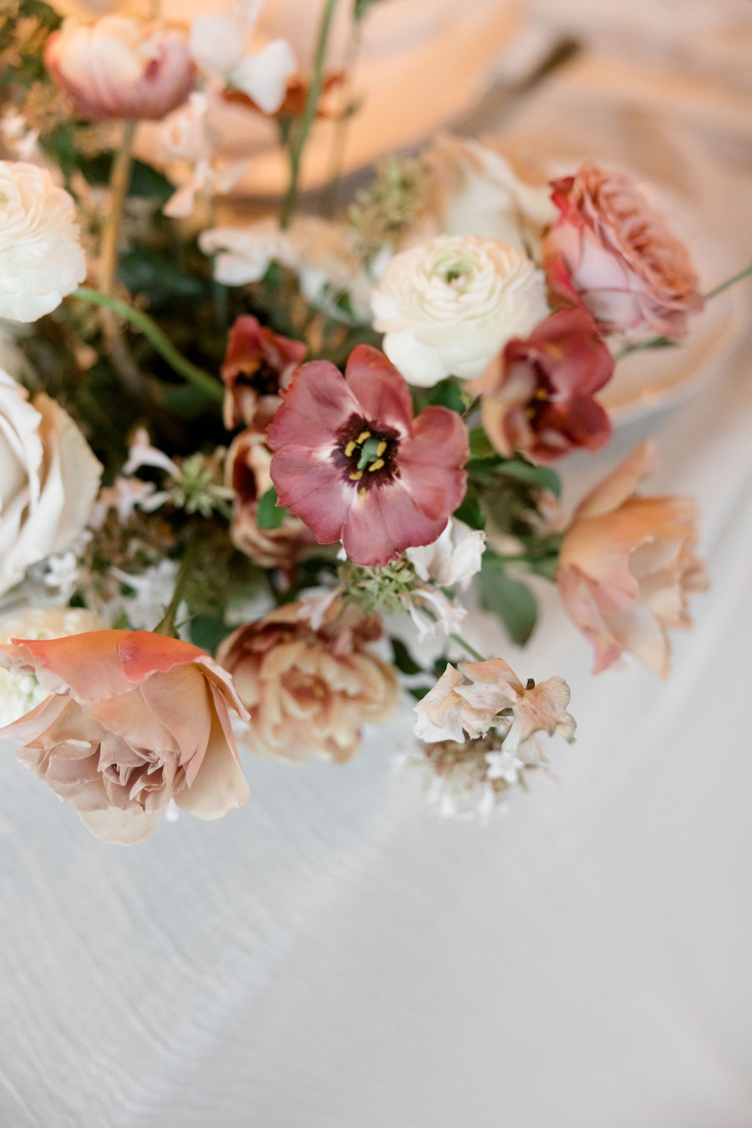 Delicate pink and white flowers arranged artistically on a light textured surface in a soft, romantic style.