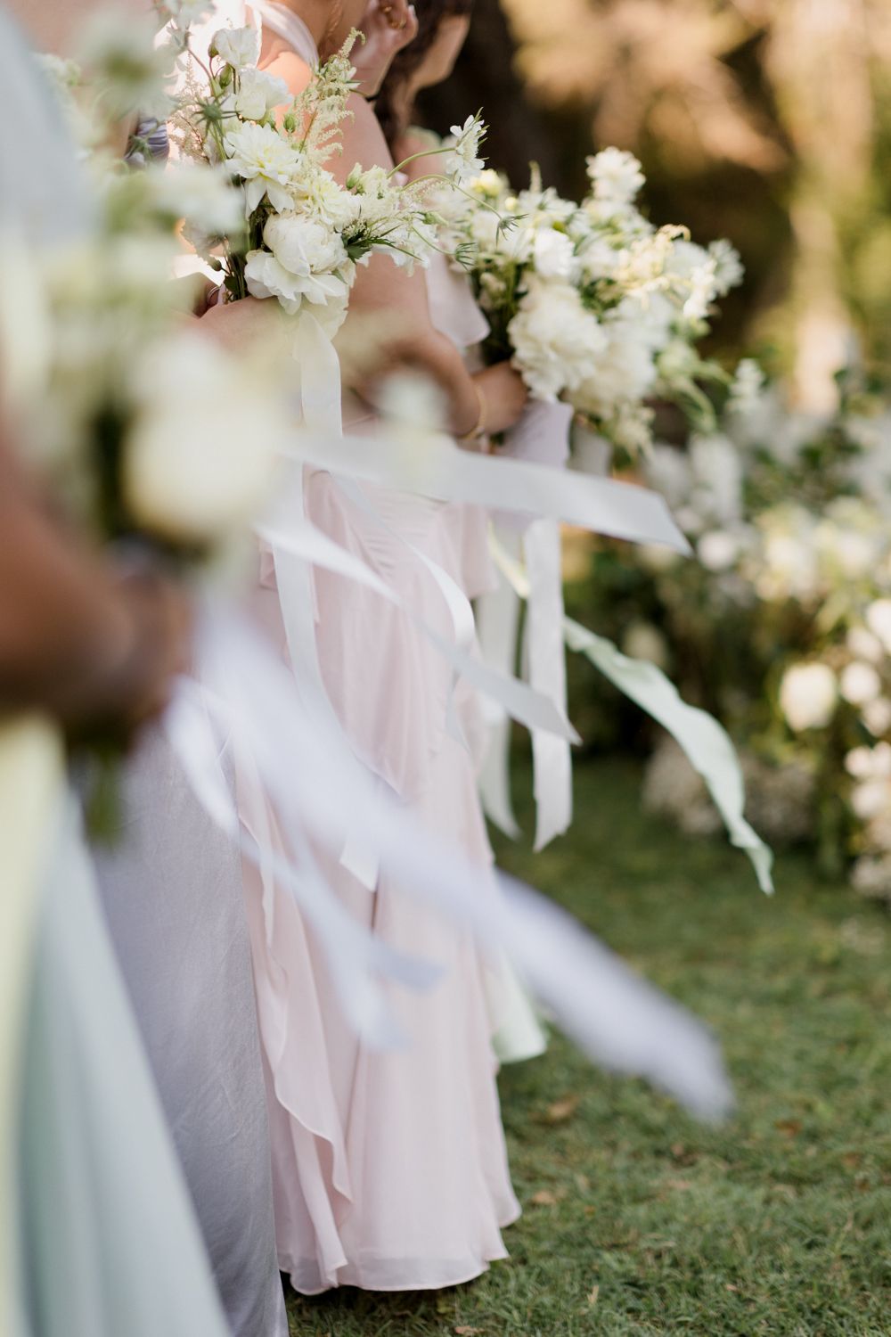 White blossoms and soft pink fabric create an ethereal outdoor wedding scene with delicate details.