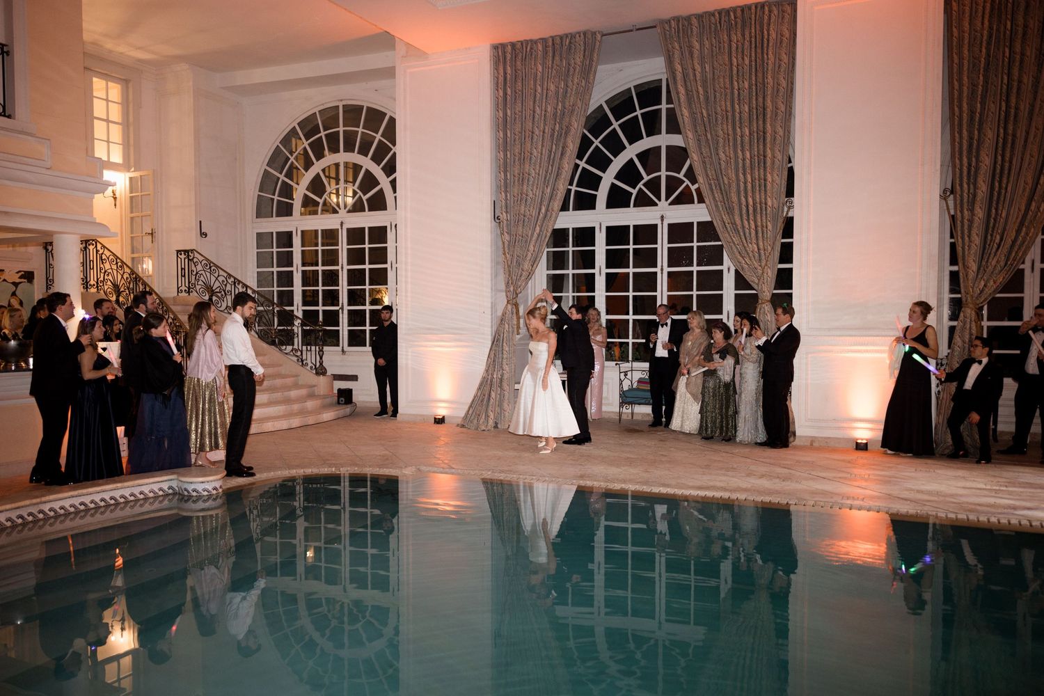 Wedding reception venue with elegant white interior and arched windows illuminated by warm ambient lighting. Château saint georges