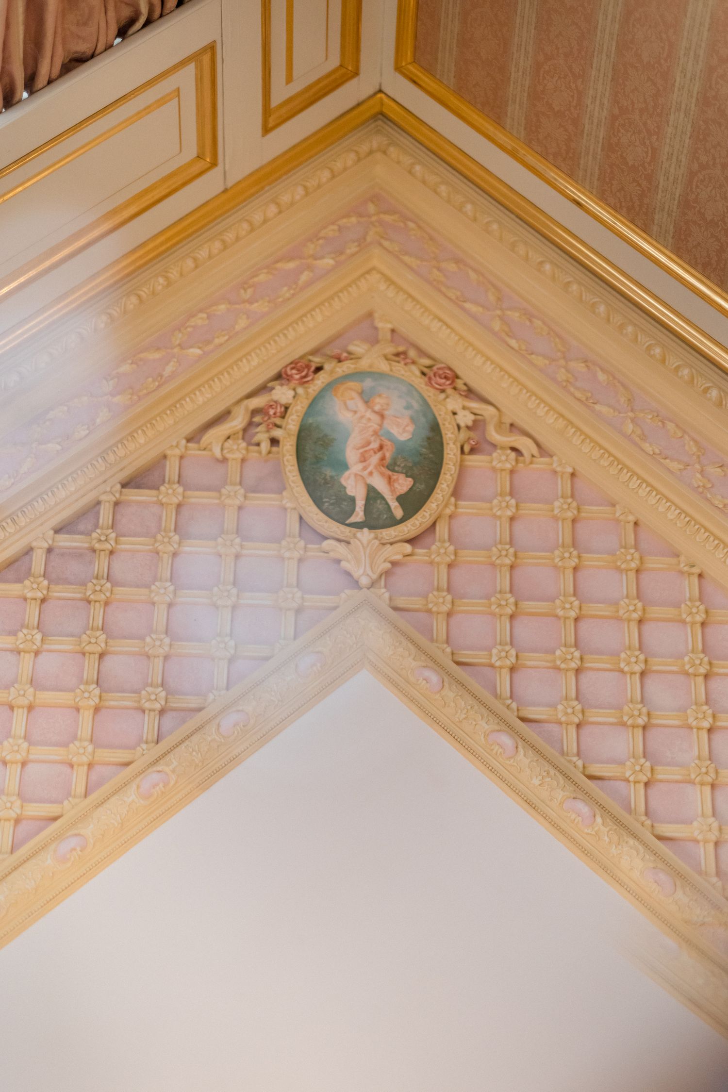 Ornate gold-trimmed ceiling detail with decorative lattice pattern and circular medallion in pale blue and cream colors.