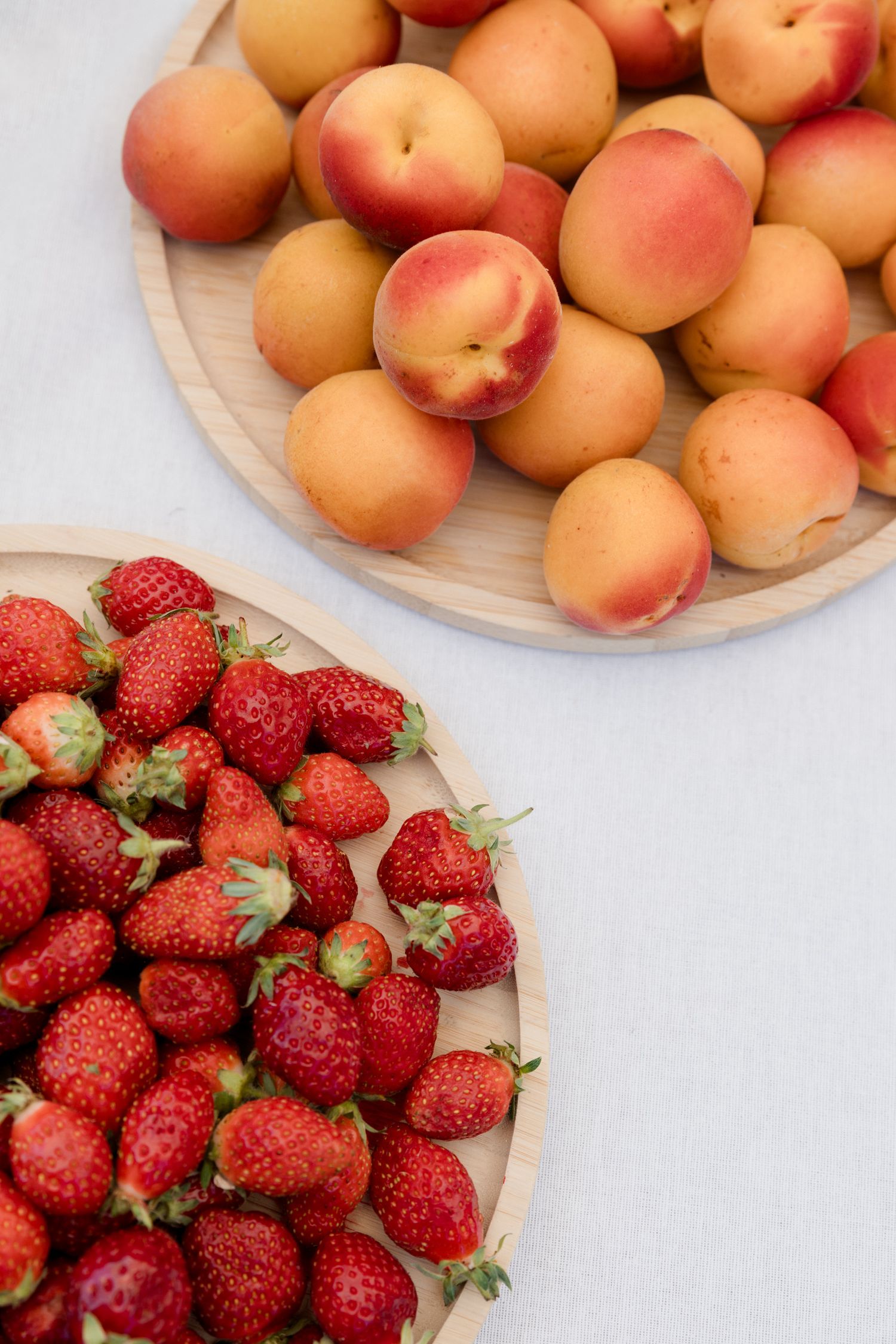 Fresh peaches and ripe red strawberries arranged on white plates against a light background. Pool party loire valley